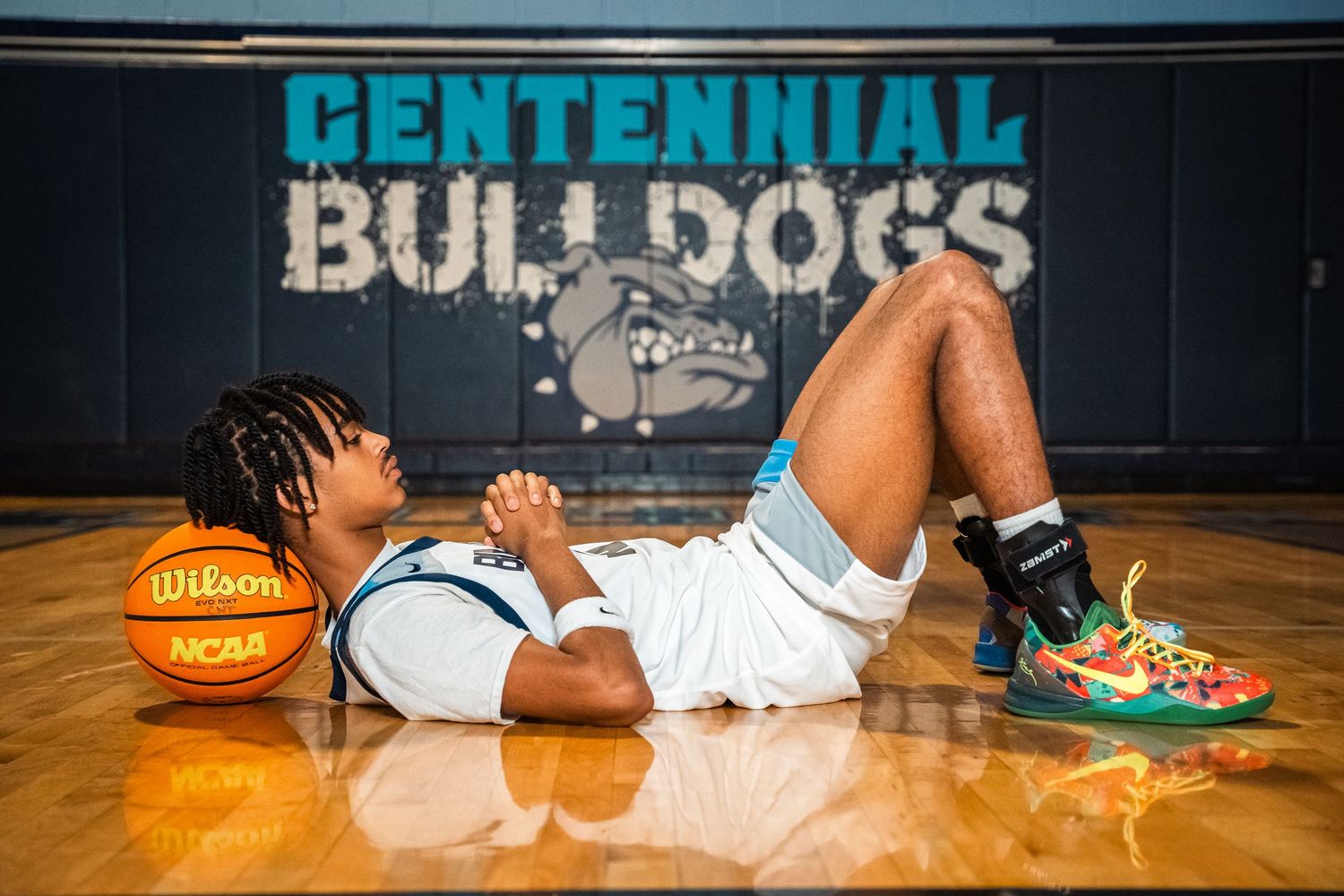 Basketball player relaxes on court floor with Wilson NCAA ball near Bulldogs logo.