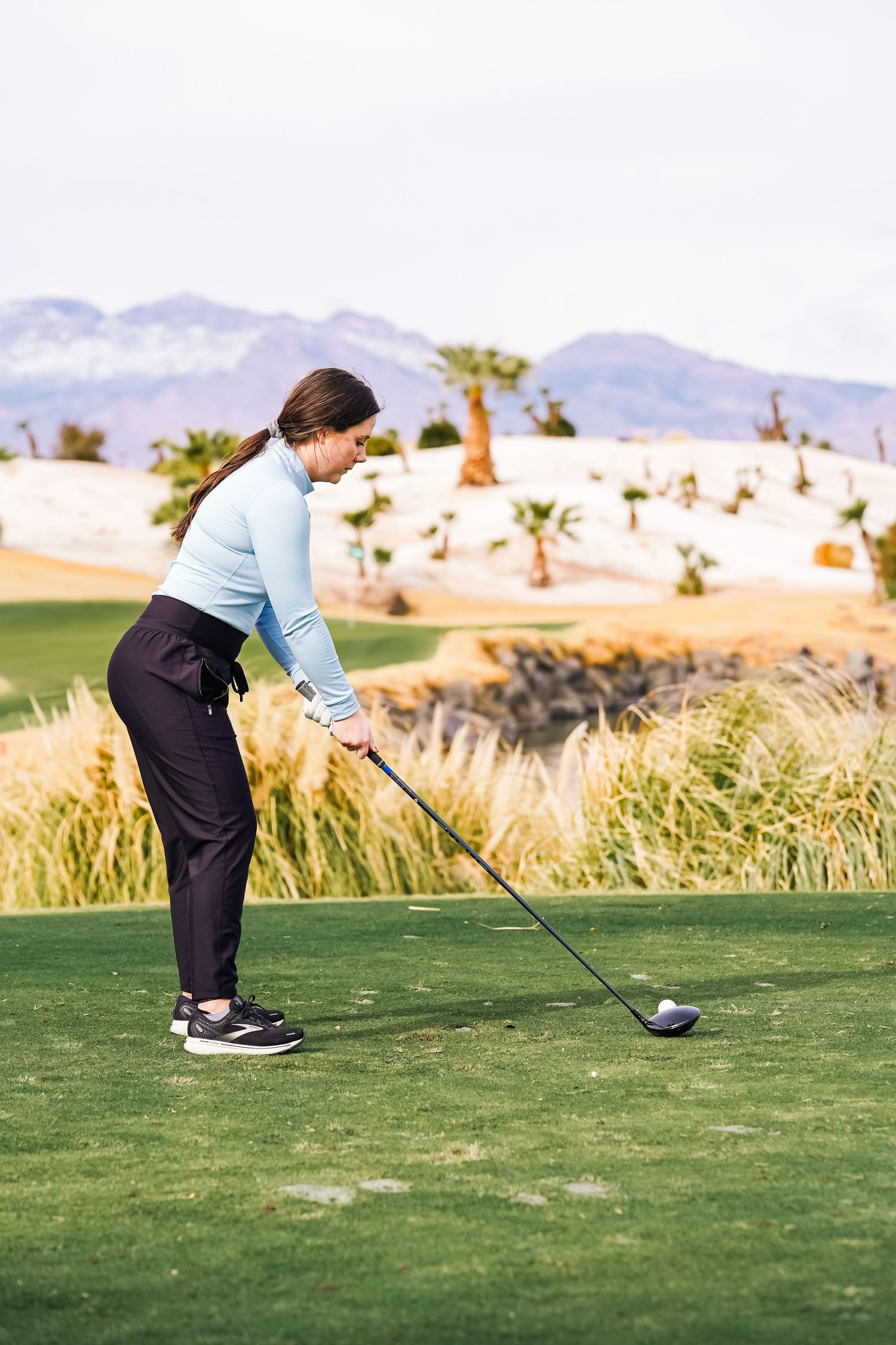 Golfer practicing their stance and swing form on a scenic desert golf course.