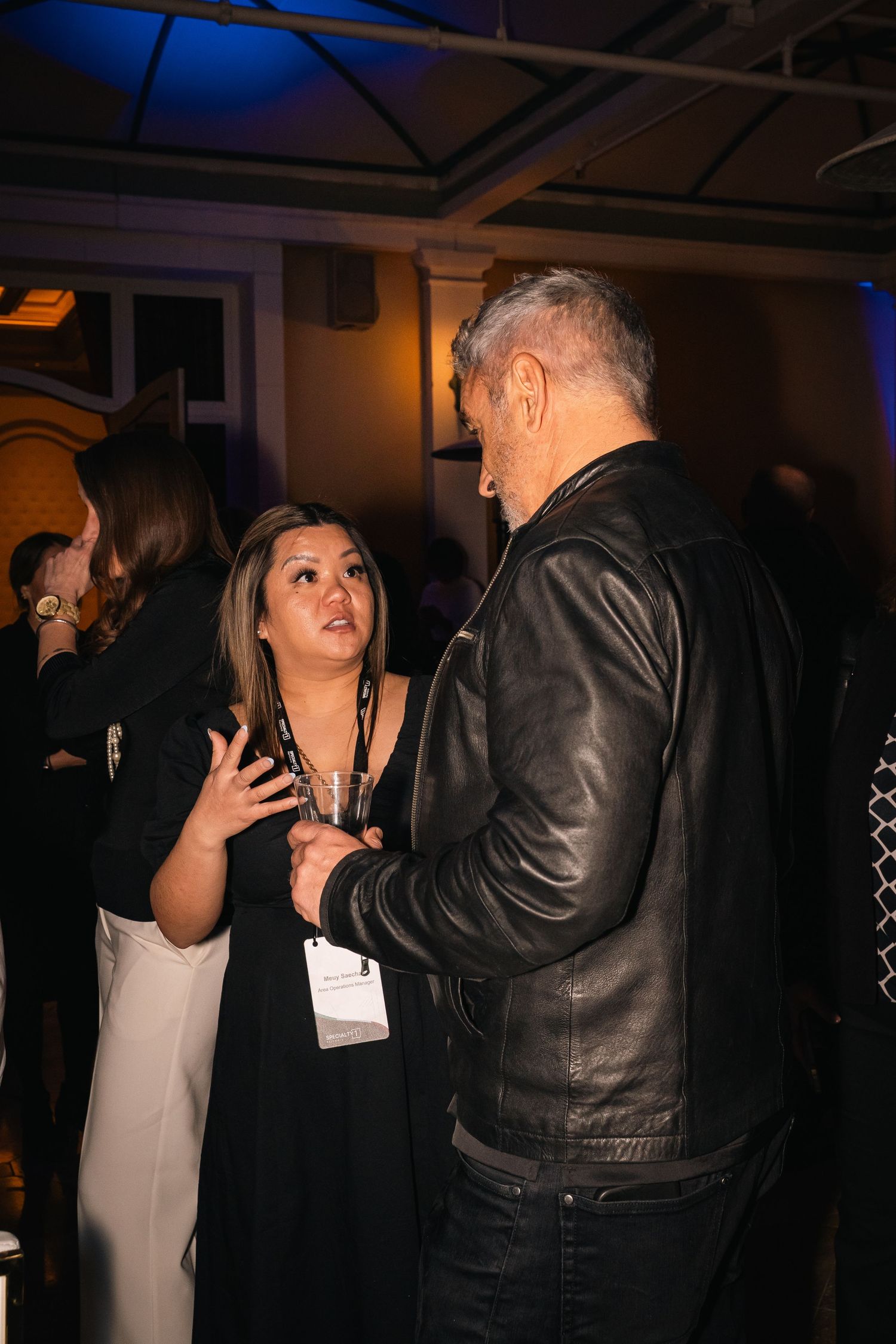 Evening networking conversation between guests at an indoor business event.