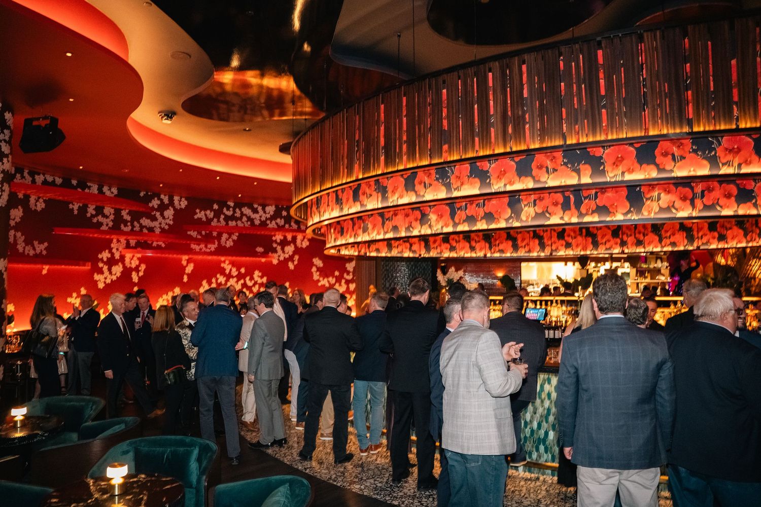 Crowded bar scene with warm red ambient lighting and illuminated wall decorations.