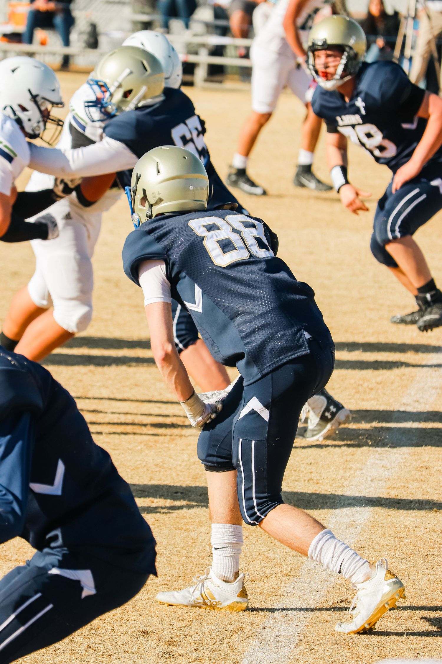 Football players in action during game with players in defensive stance.