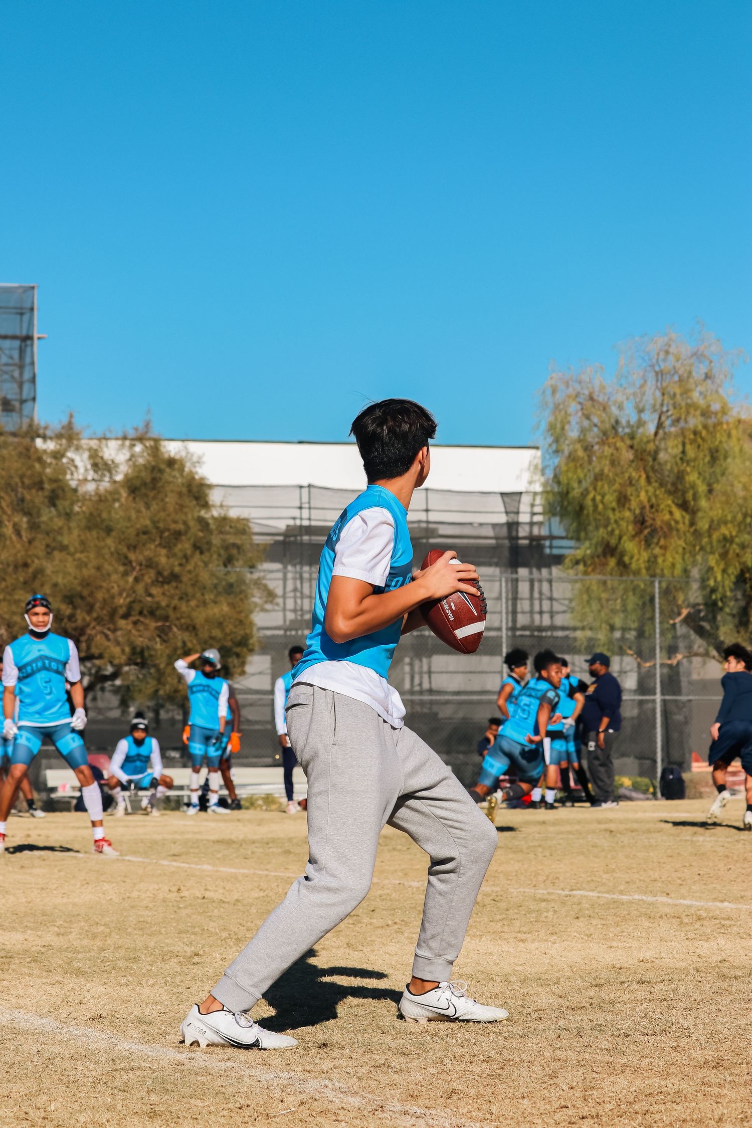 Athletes performing coordinated training exercises on dry grass field under blue sky.
