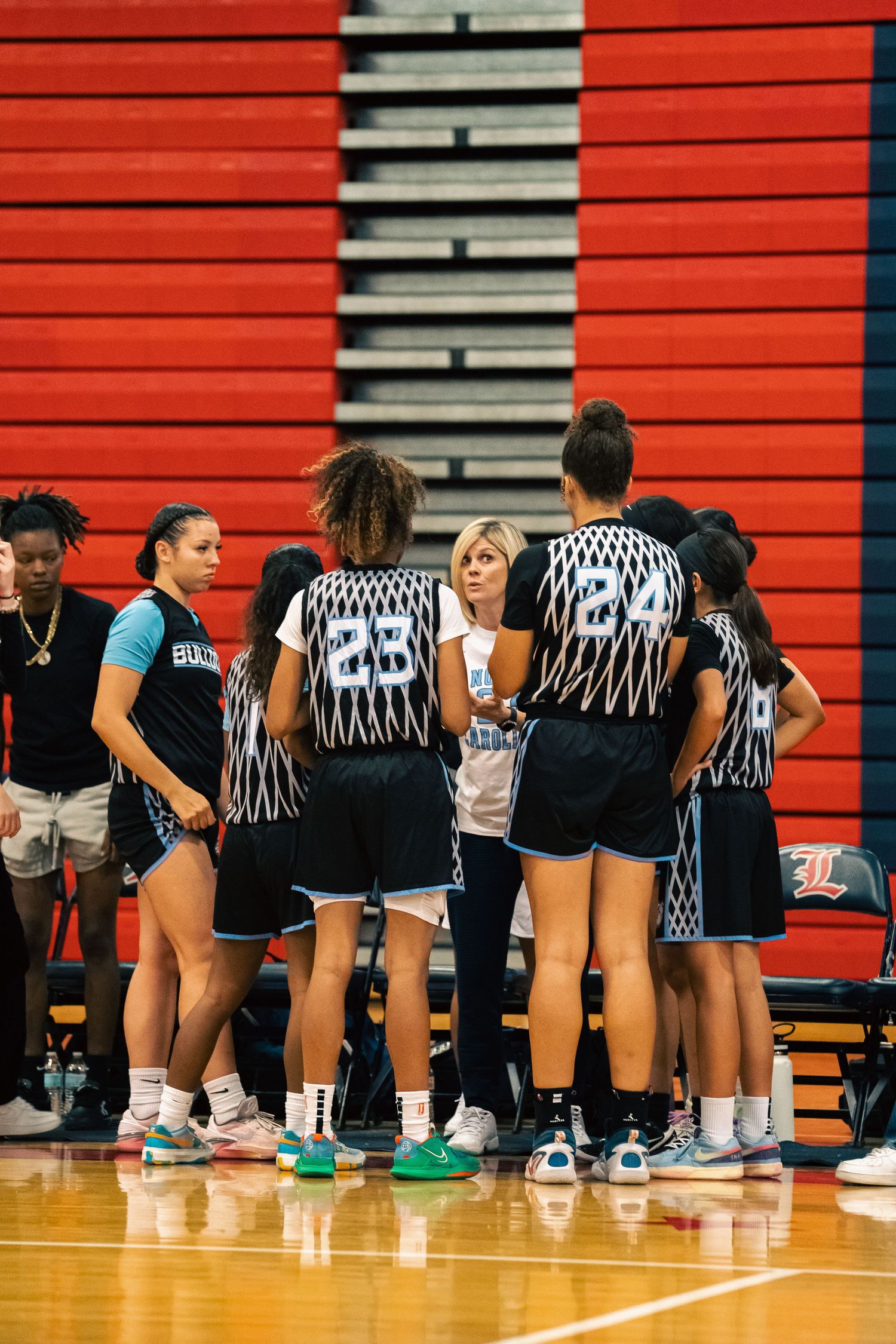 Basketball team lines up on a gymnasium floor wearing black and white uniforms.