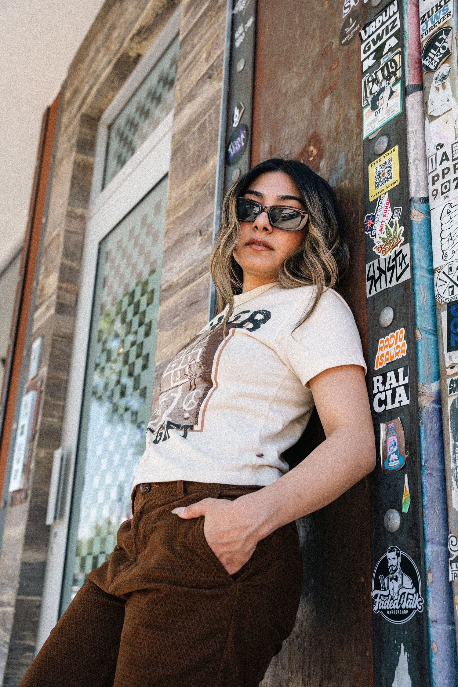 Cool urban fashion pose against graffiti wall wearing Honor t-shirt and vintage brown pants.