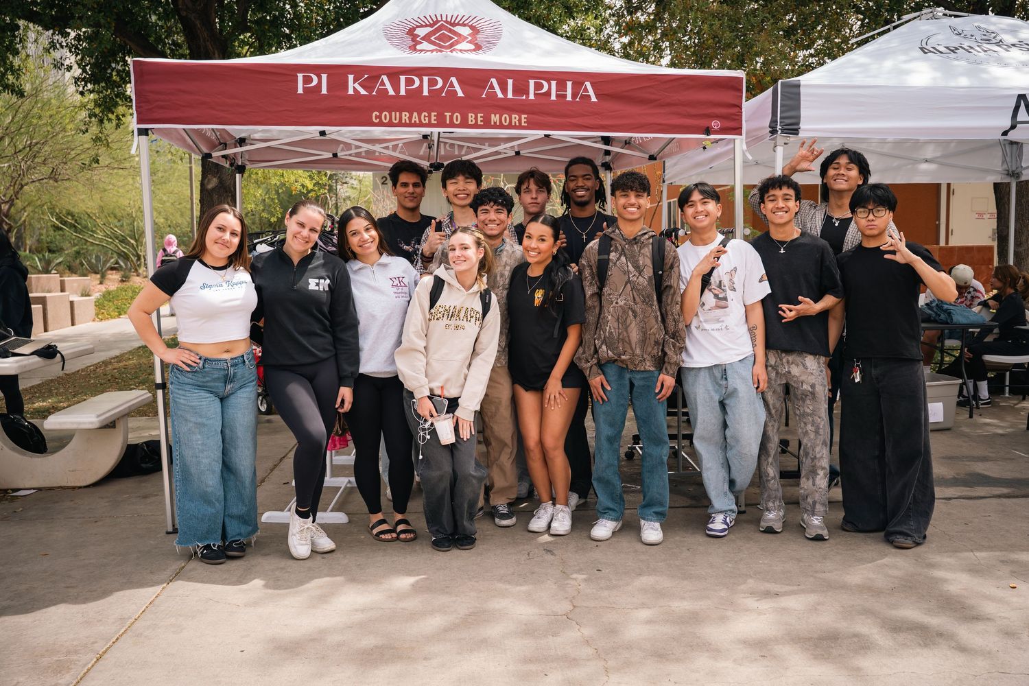 Students pose together under a Pi Kappa Alpha banner at a campus organization fair.