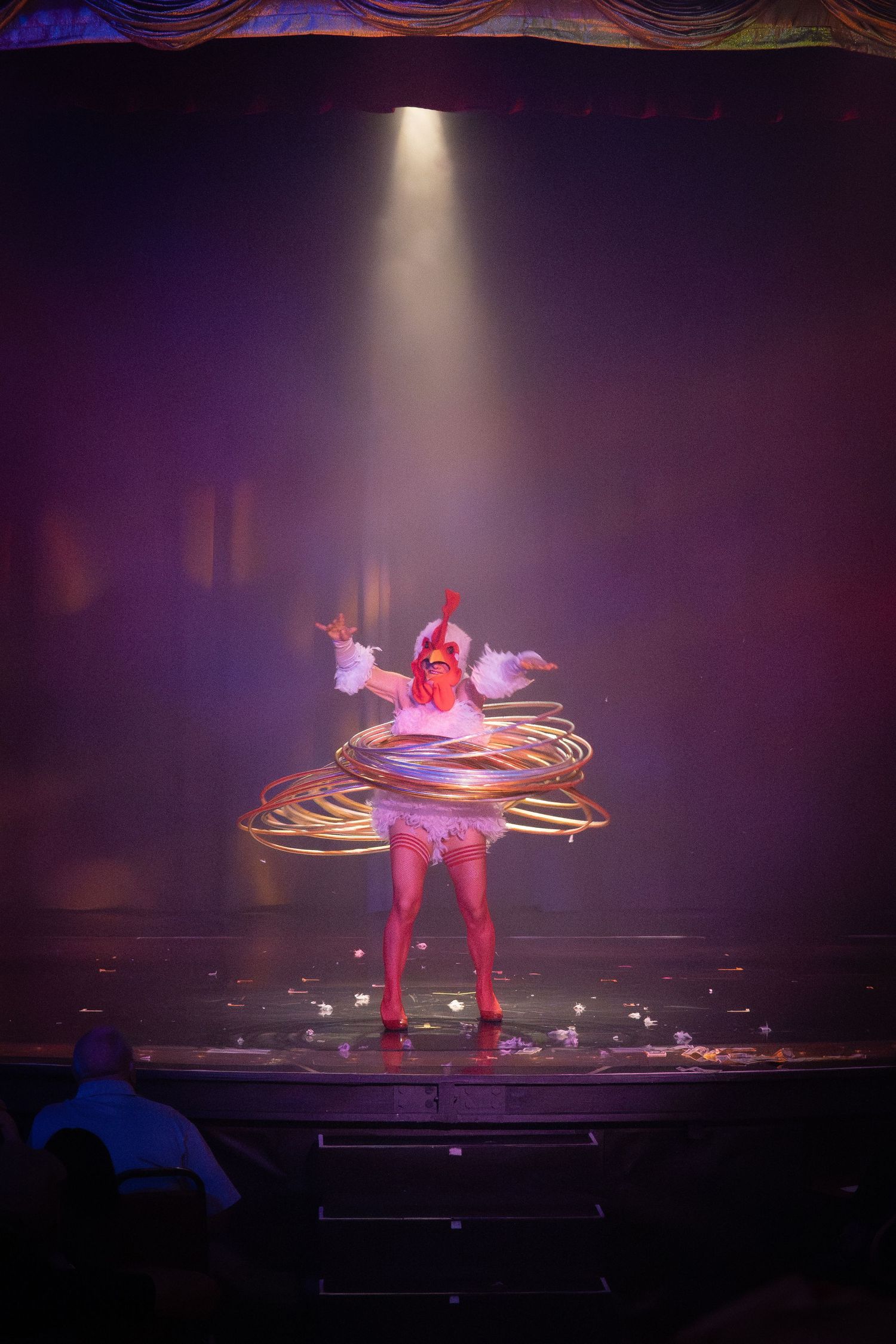 Burlesque performer spinning with illuminated hoop under spotlight.