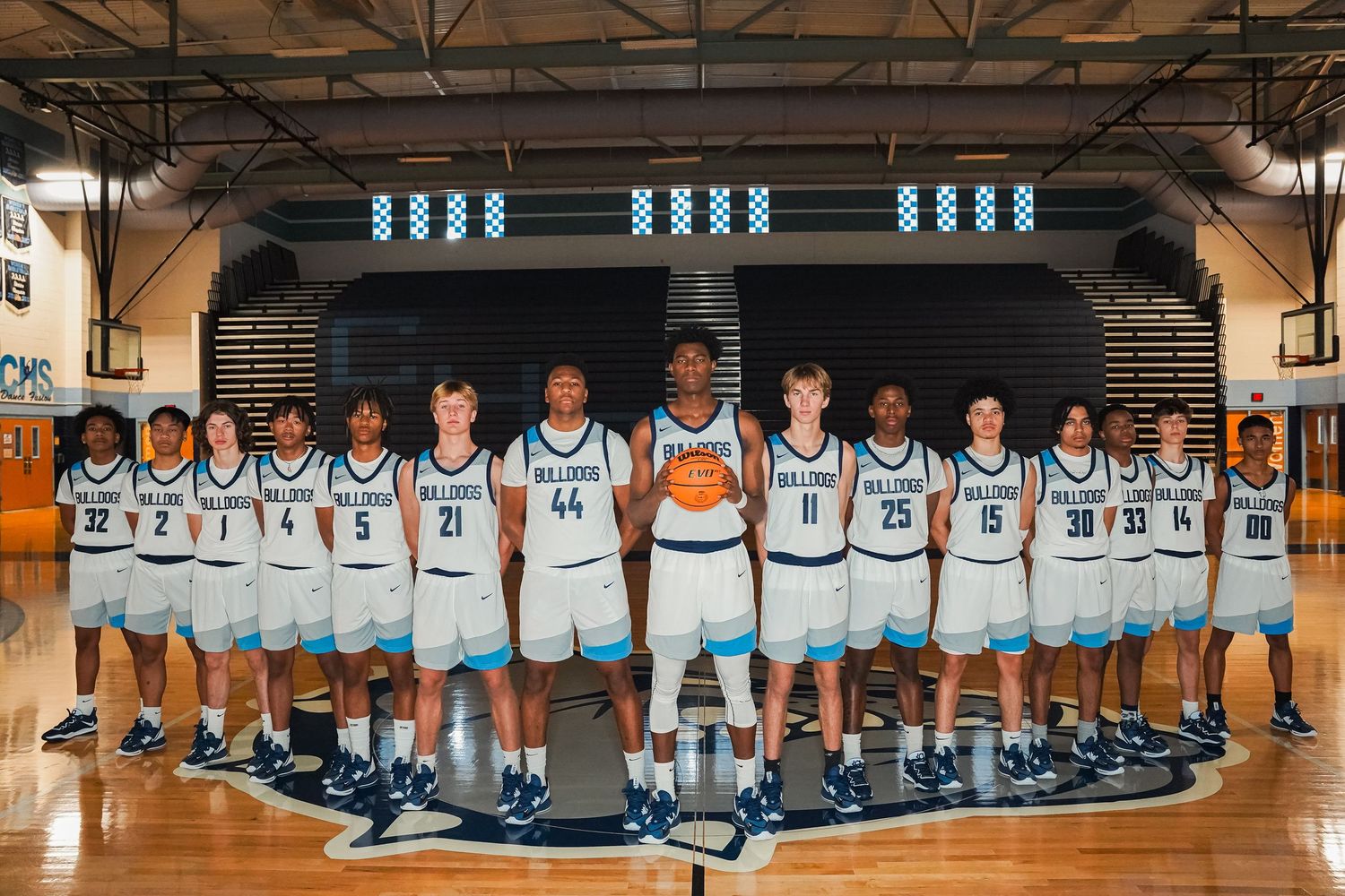 Full basketball team photo of Centennial Bulldogs players lined up in home white uniforms.