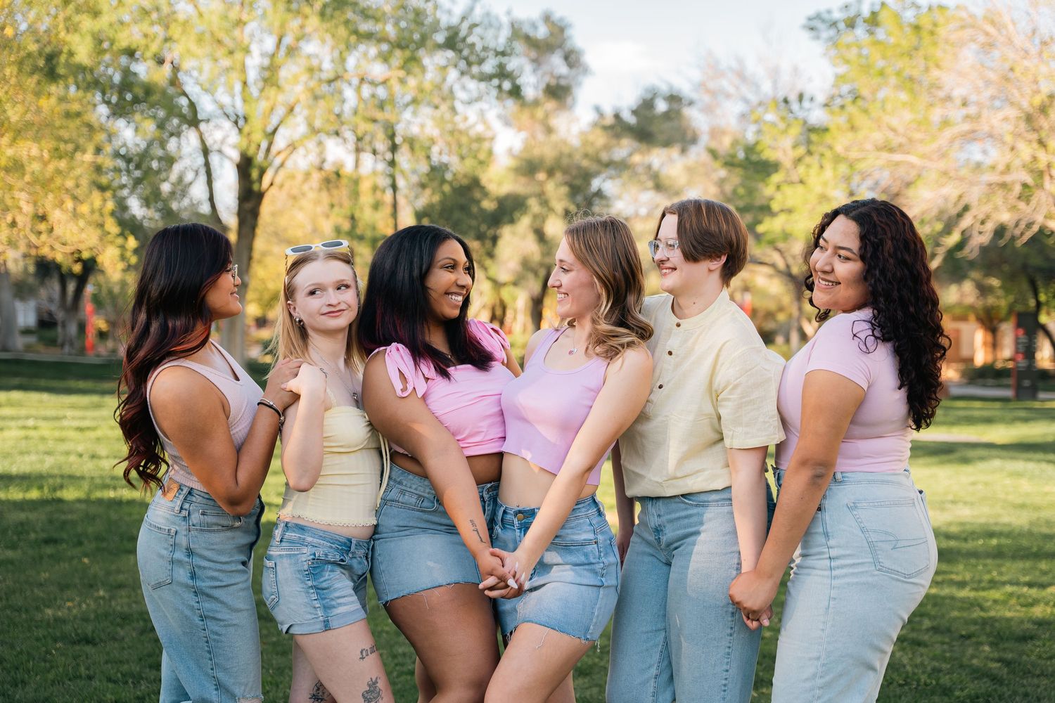 A group shares a playful moment together wearing coordinated casual outfits in an outdoor setting.