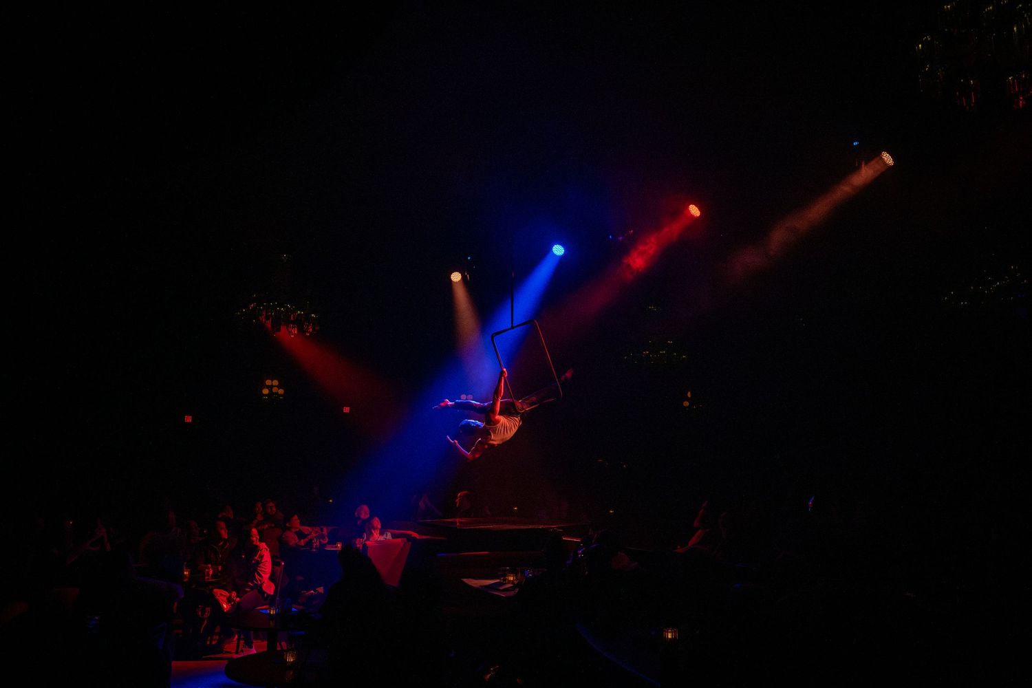 Colorful stage lights create dramatic beams of red and blue in a dark performance space.