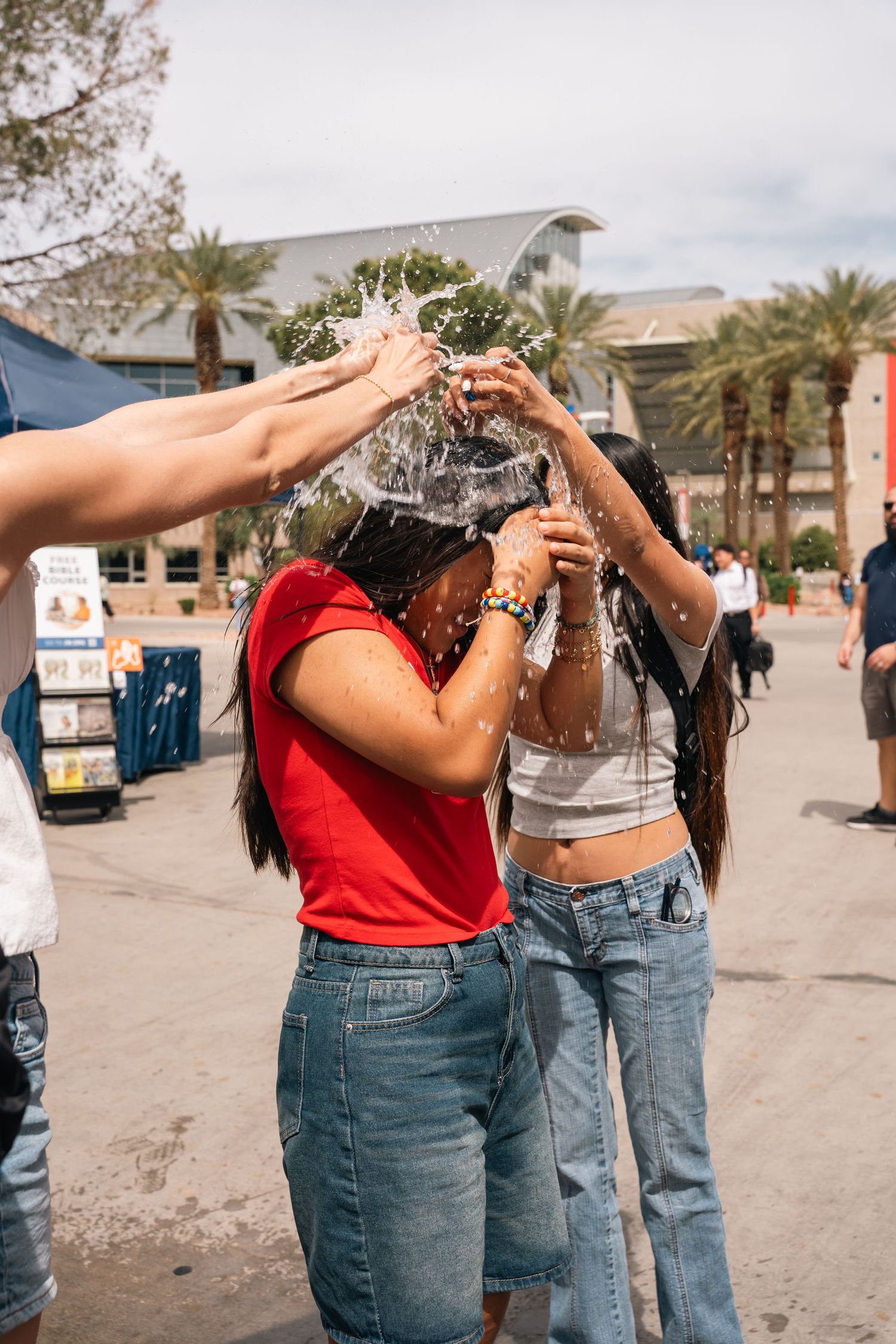Students splash water during a fun outdoor campus activity on a sunny day.