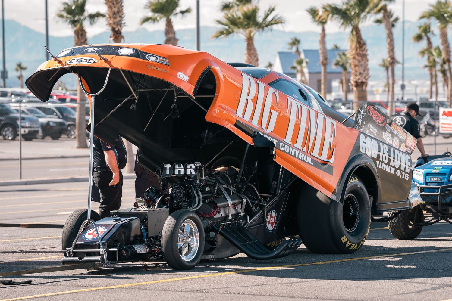 Orange Big Time dragster with lifted front end on display at outdoor motorsport event.