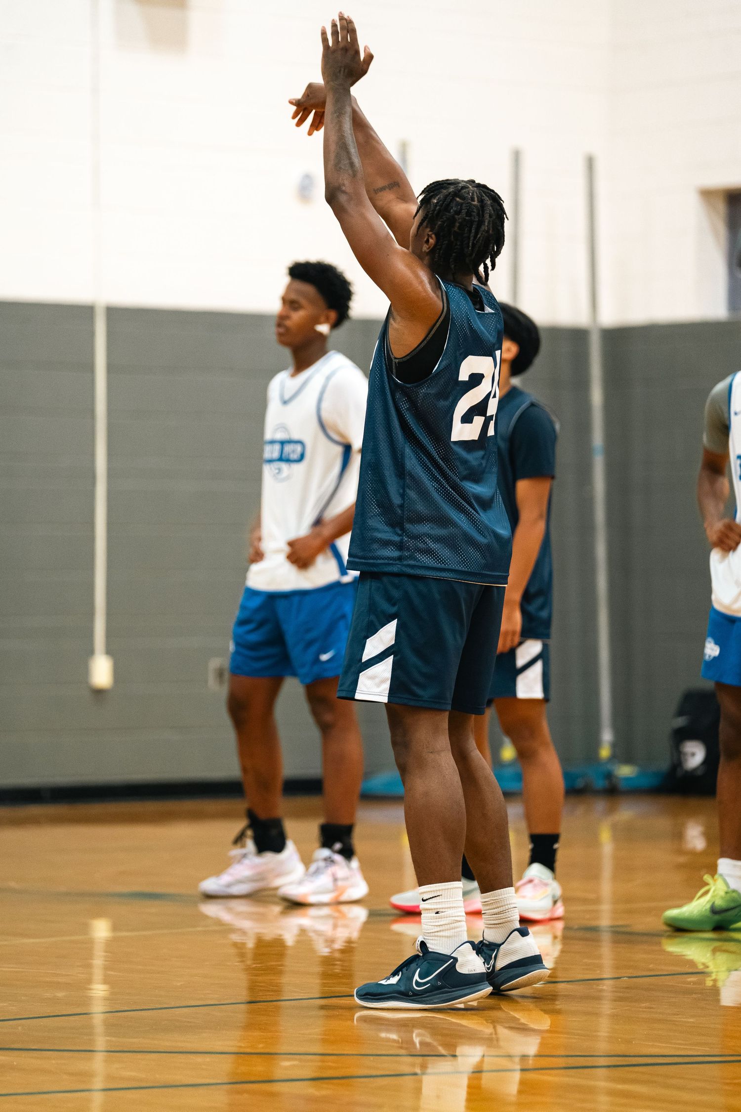 Player in navy jersey raises arms during basketball game.