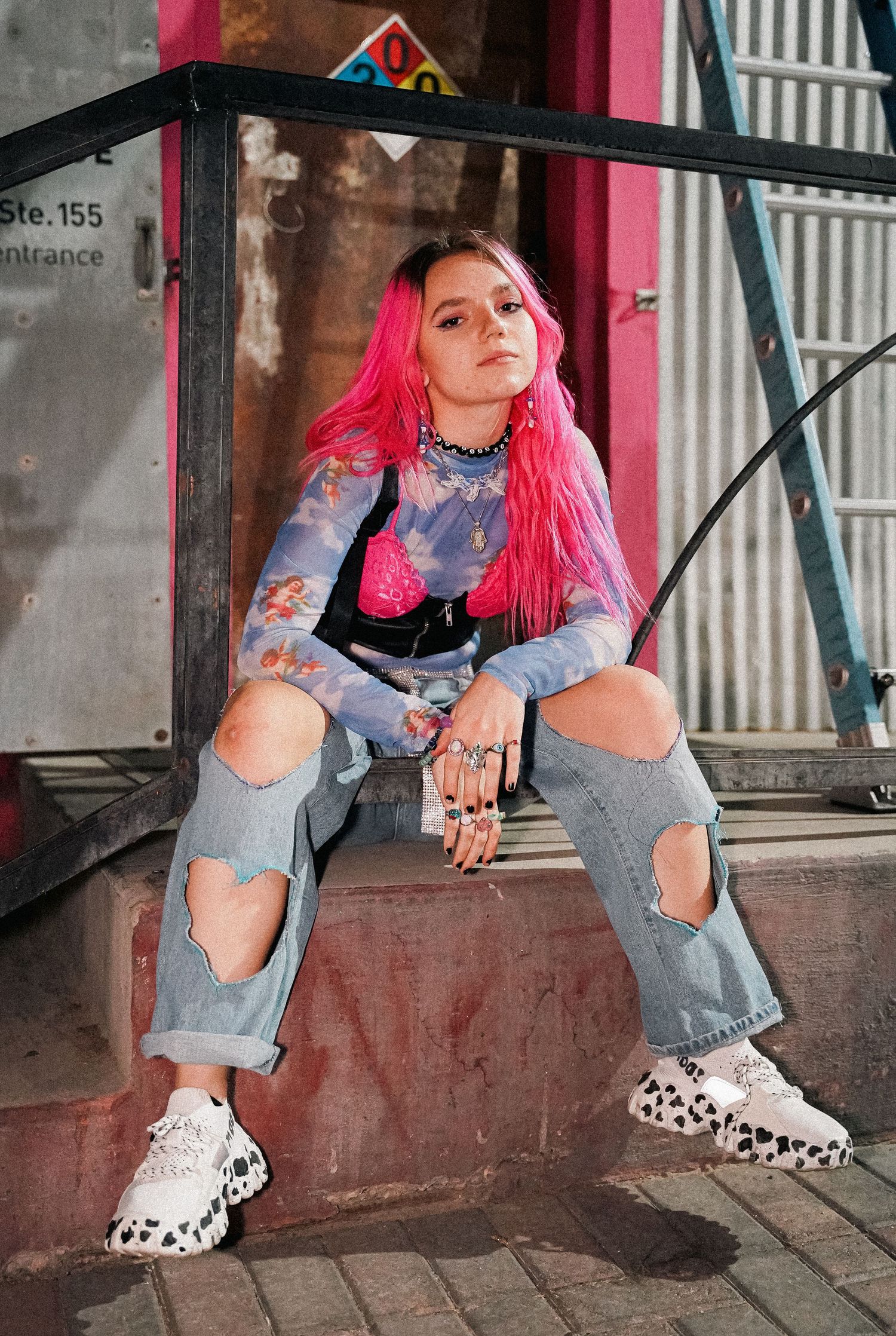 Urban fashion photography featuring ripped jeans and animal print shoes against industrial backdrop.