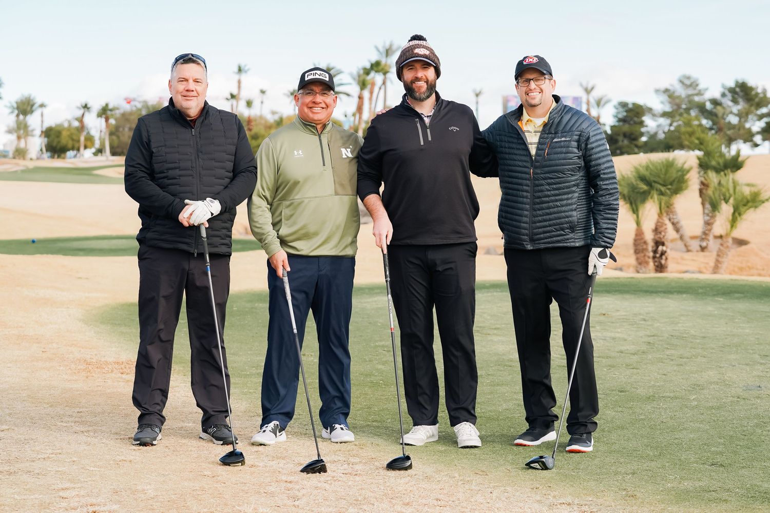 Group of golfers lined up on the fairway of a desert golf course.