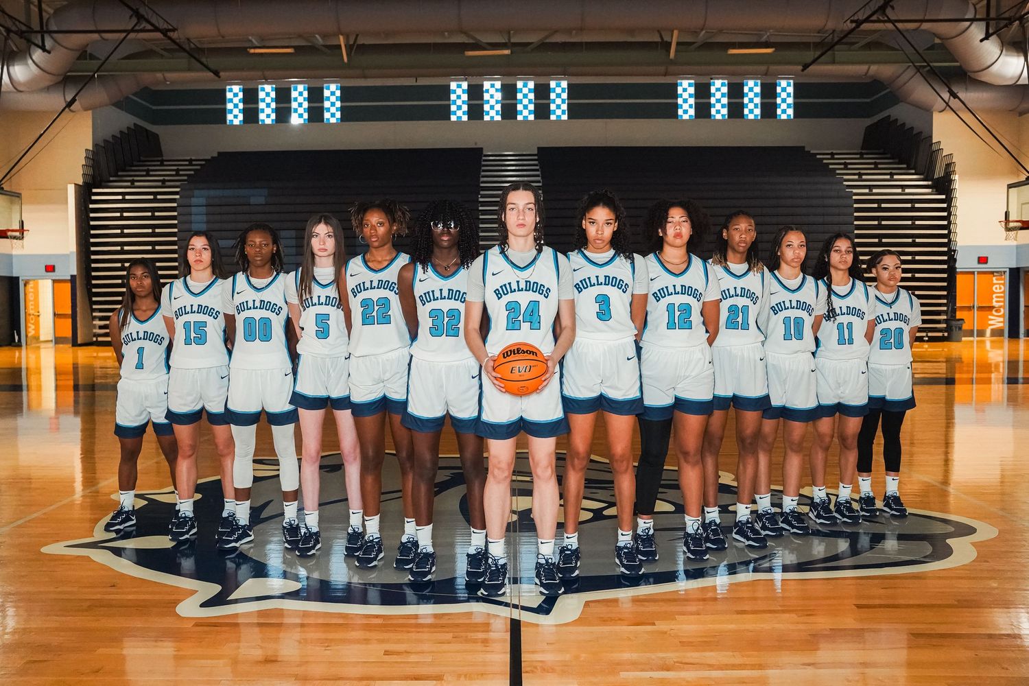 Centennial Bulldogs basketball team poses for official team photo on court.