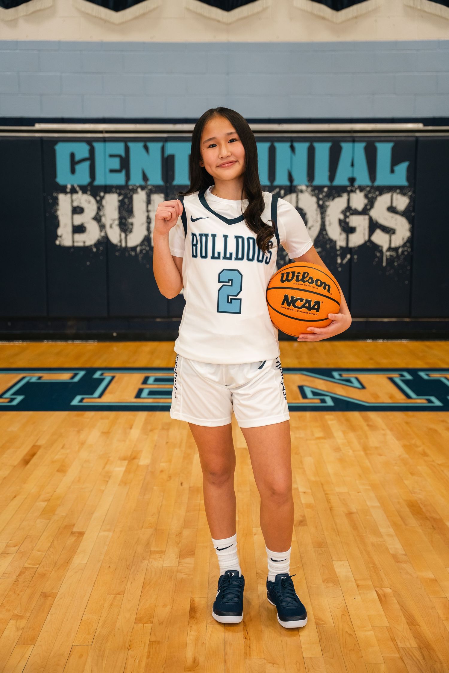 Young basketball player in white Bulldogs uniform number 2 poses with Wilson NCAA basketball.