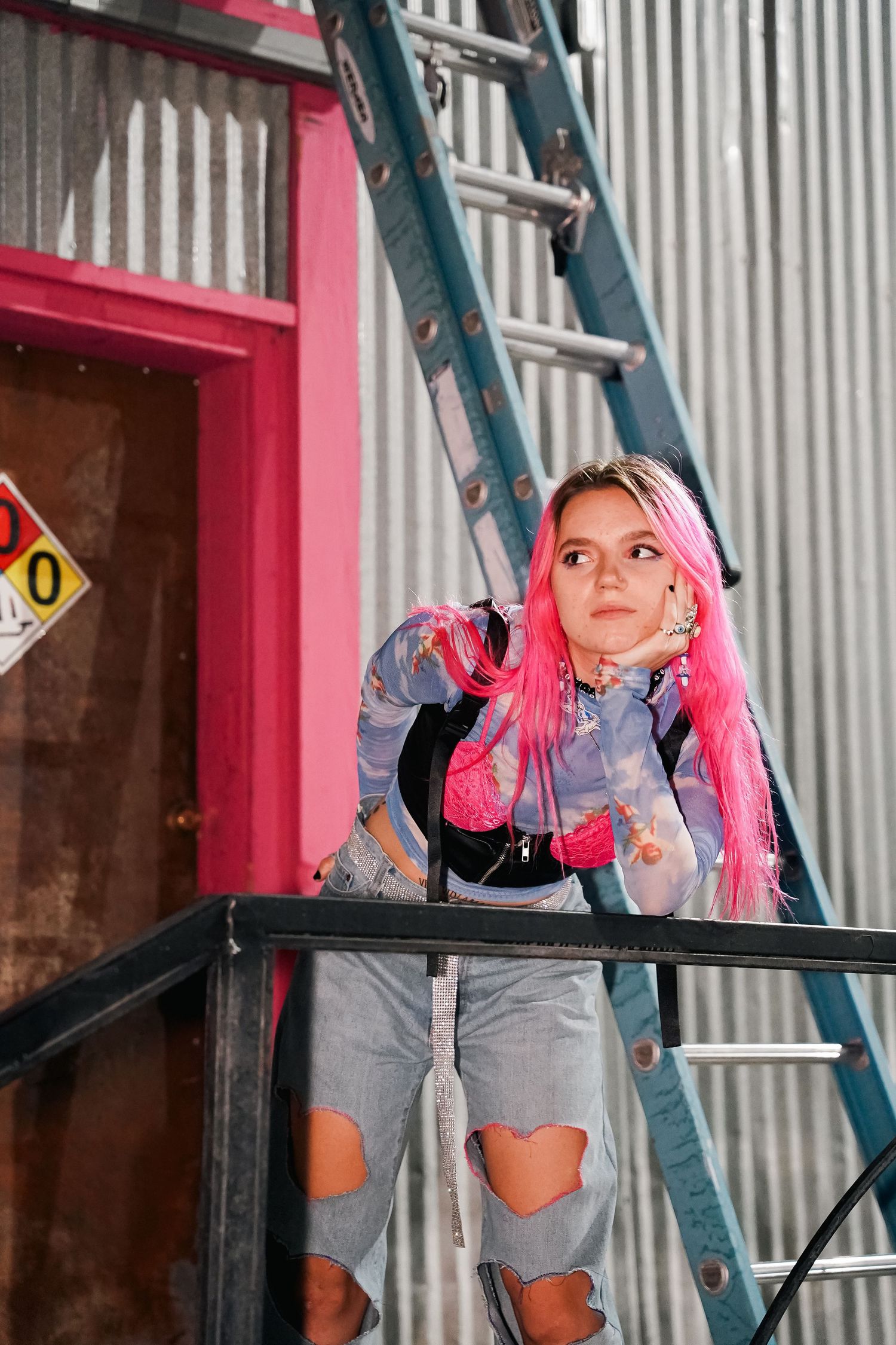 Creative fashion shoot on industrial metal stairs with pink architectural elements.