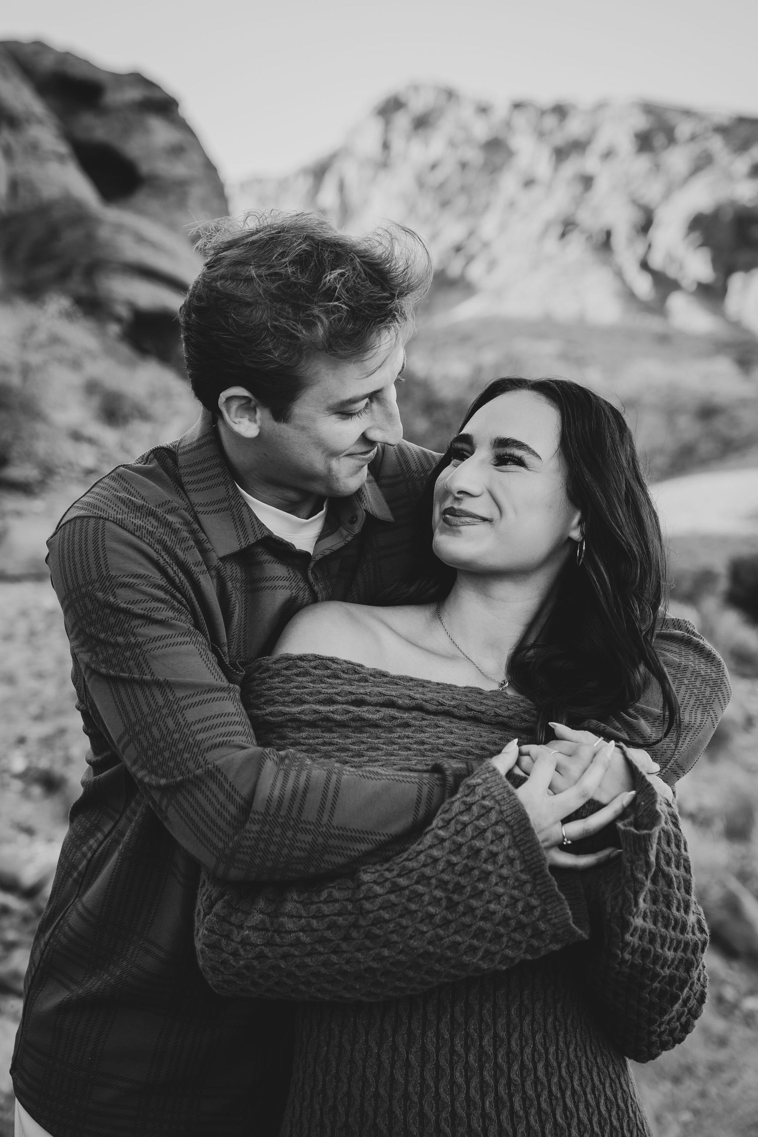 An intimate black and white portrait of a couple sharing a tender moment in the mountains.