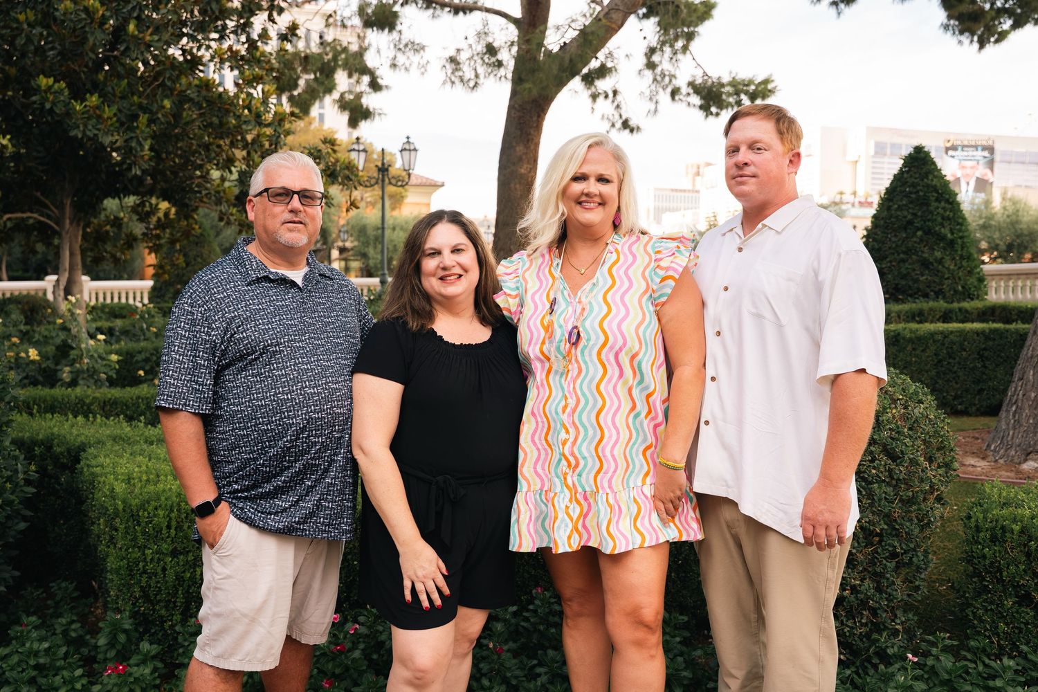 Small group poses for casual photo on landscaped garden path.