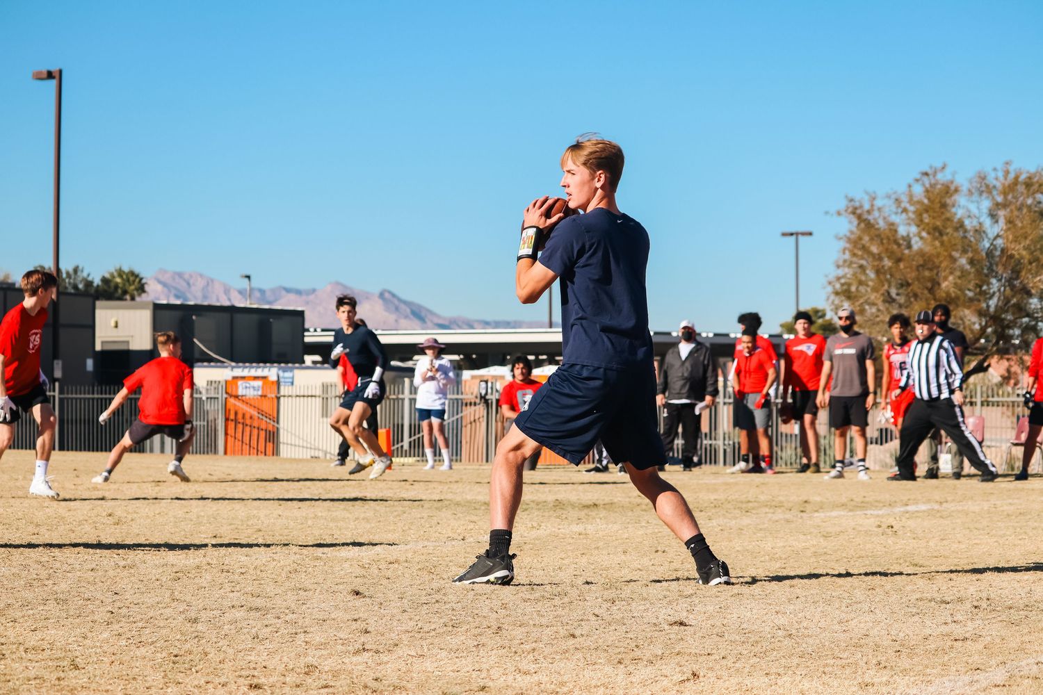 A player in navy shorts throws a football during an outdoor game.