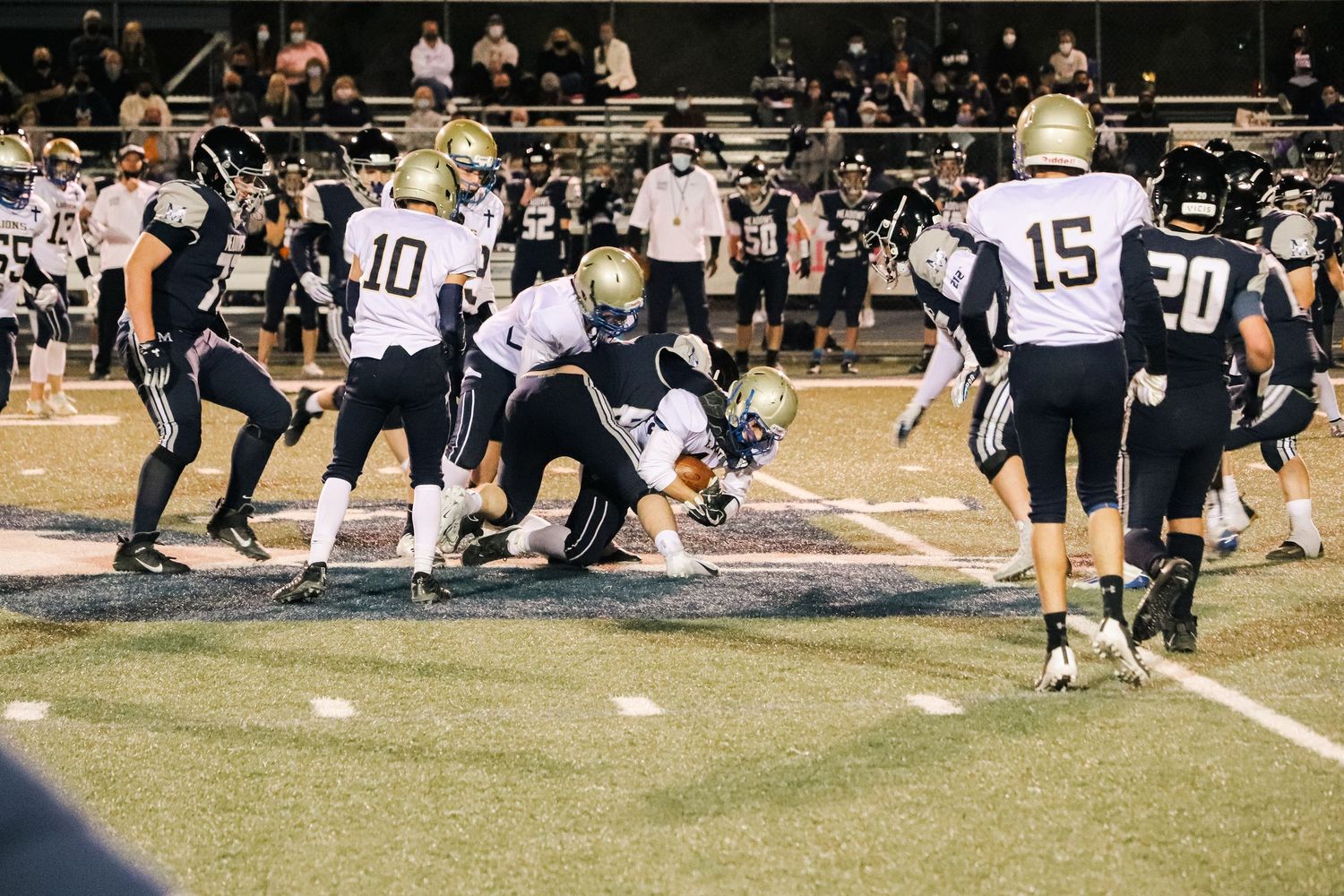 Football players competing on a grass field at night during a game.