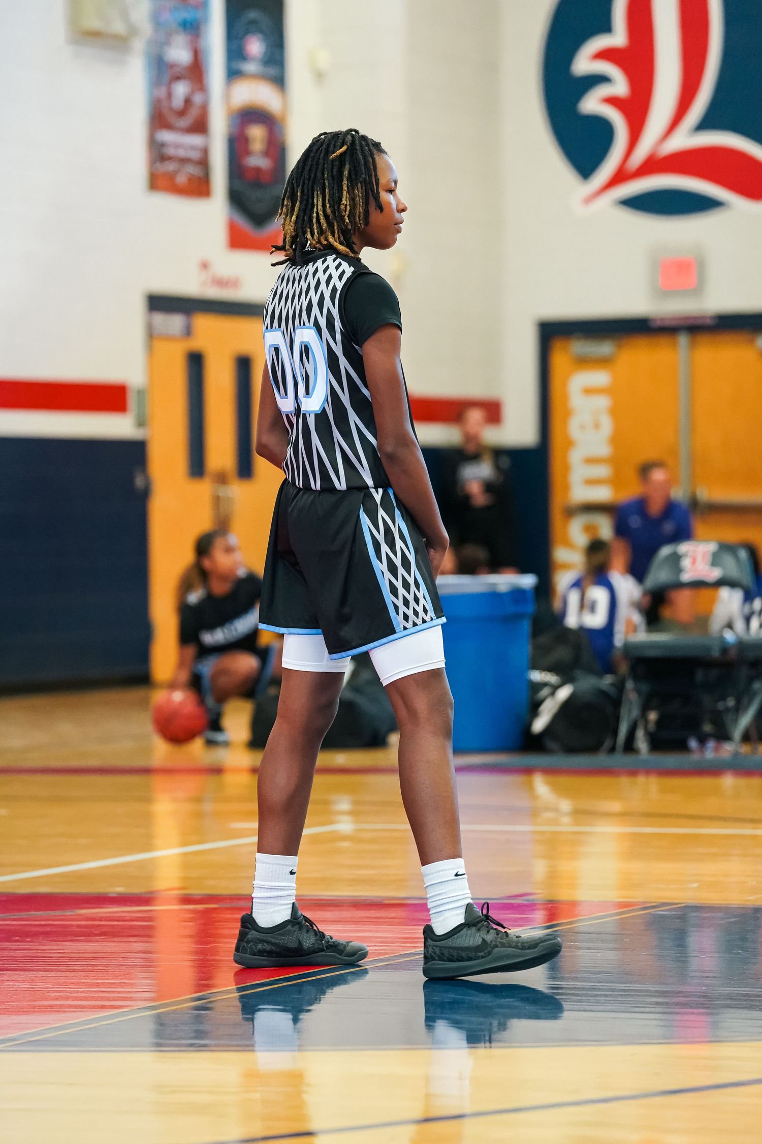 Close-up of basketball player's legs and shoes on gymnasium court during practice.