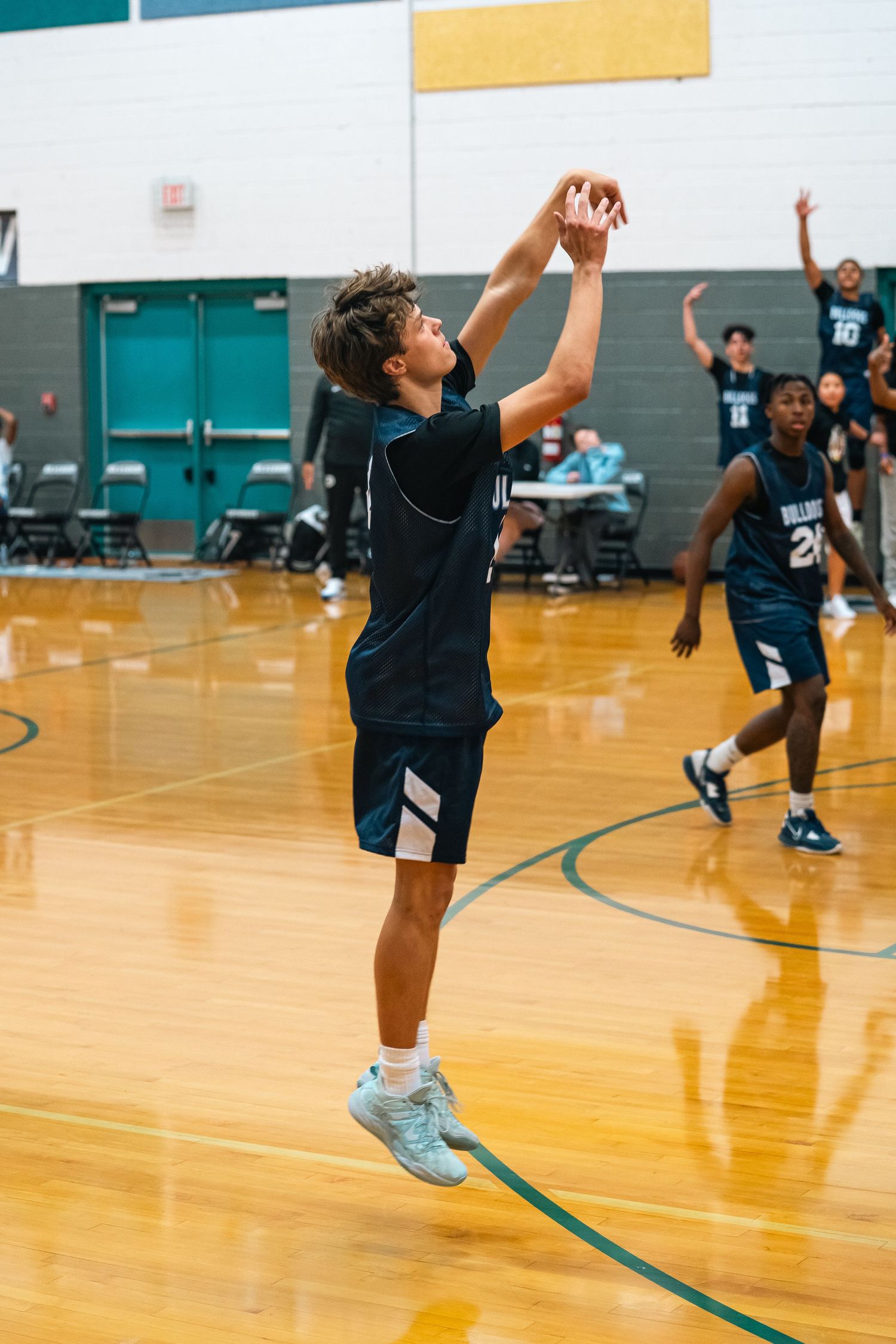 Basketball players practicing drills and stretching exercises on a gymnasium court.