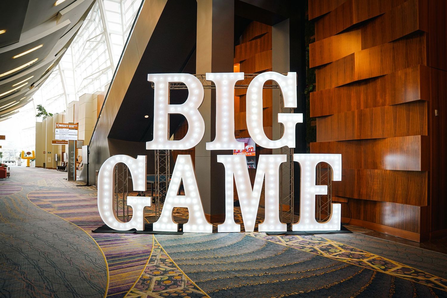 Large white 'BIG GAME' text display in a modern casino hallway with wooden wall panels.