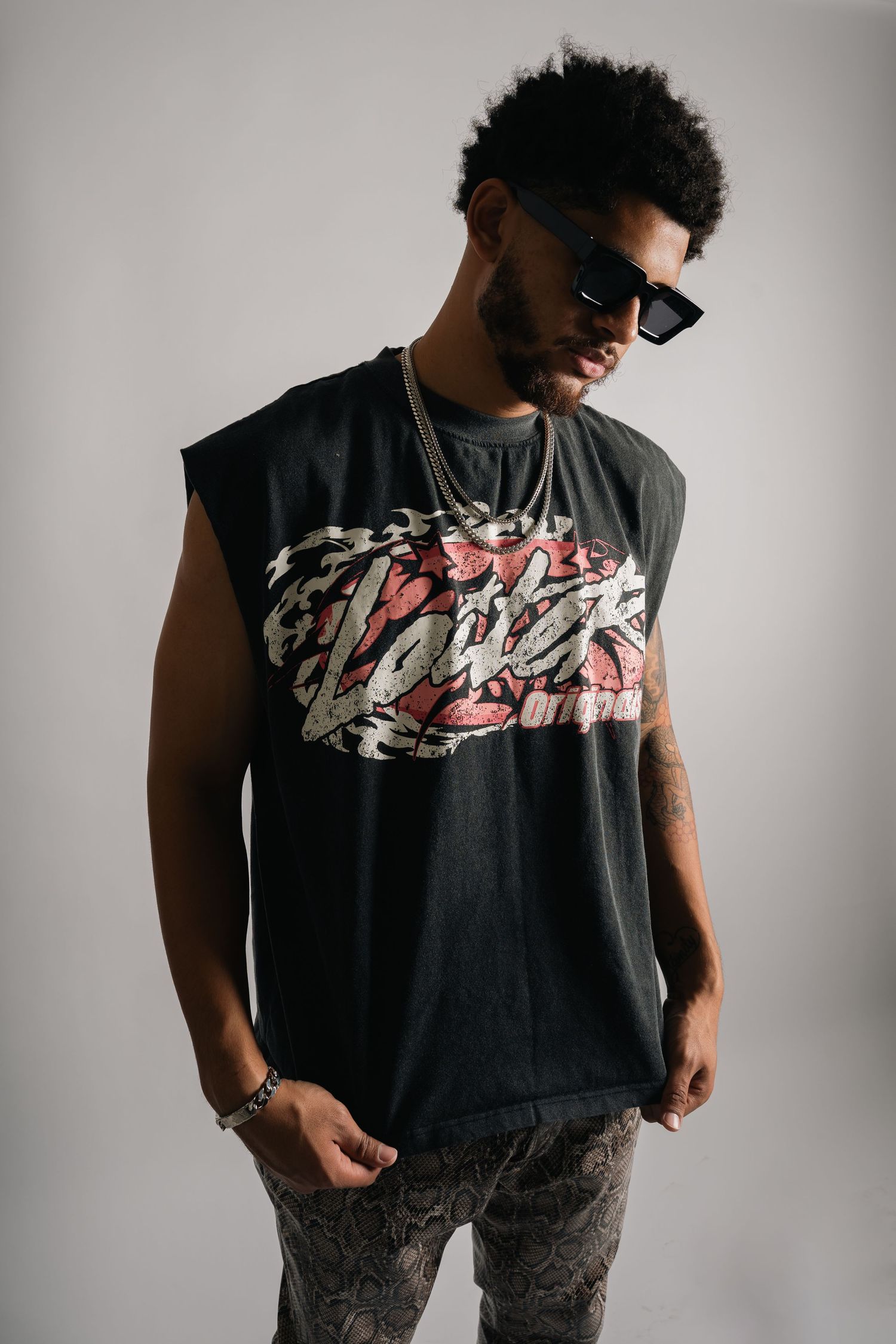 Studio shot of streetwear fashion featuring black graphic t-shirt and patterned pants.