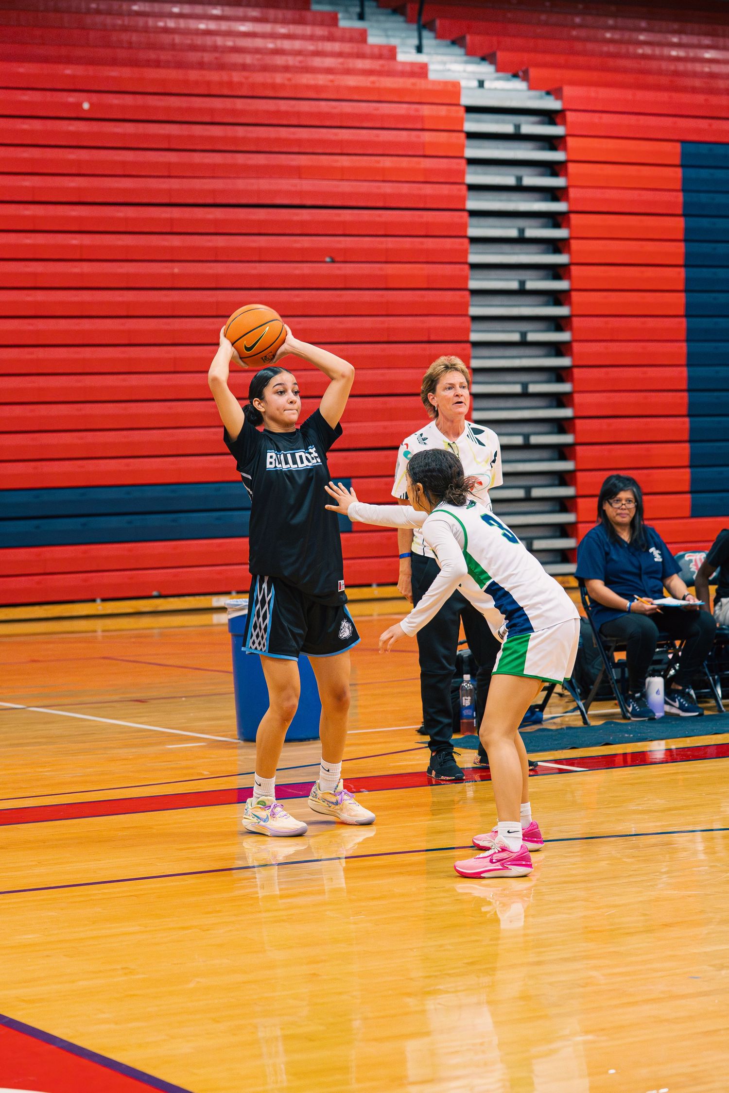 Youth basketball game action shows player preparing to shoot while defender guards.