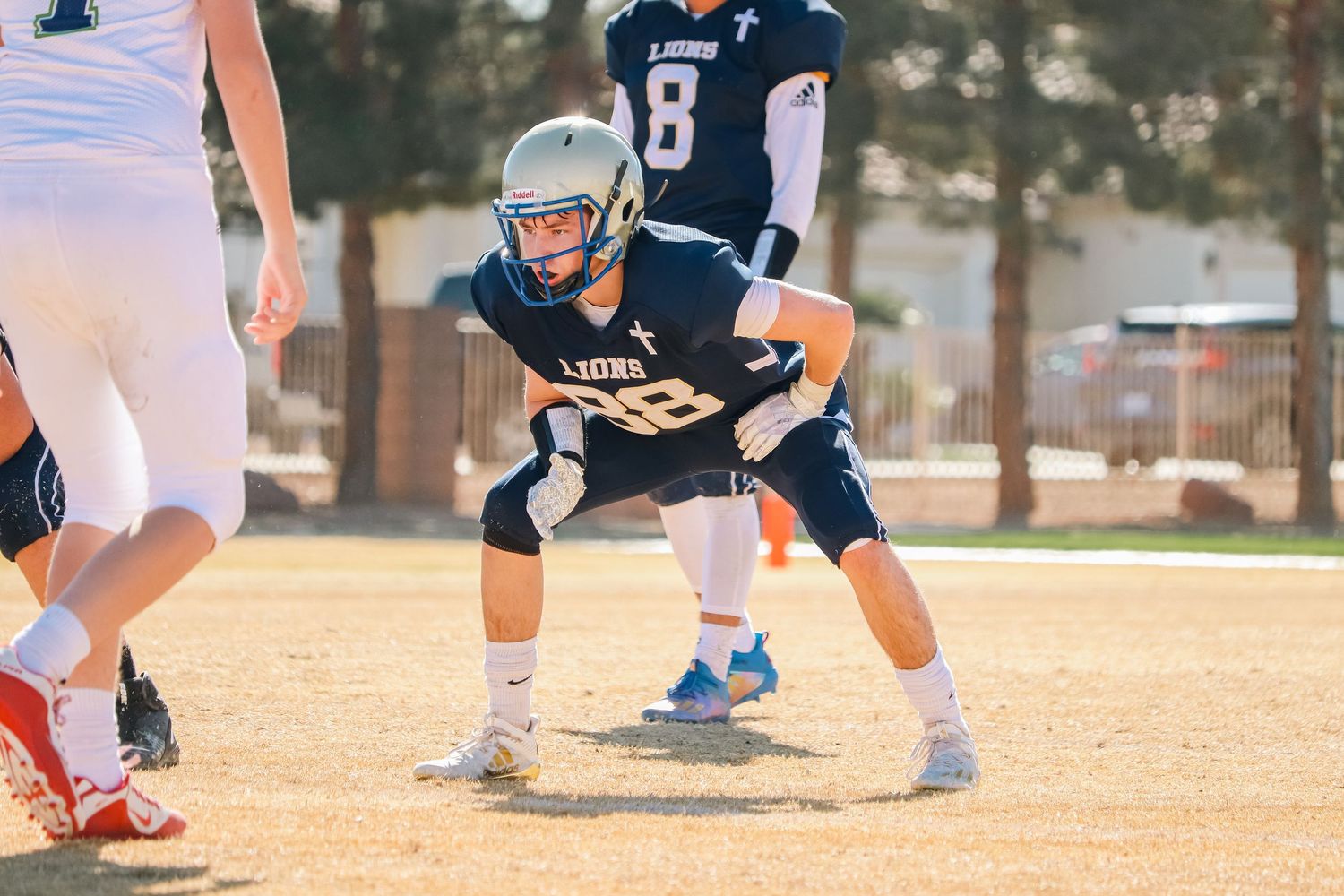 Football player in crouching stance ready for snap during sunny game day.