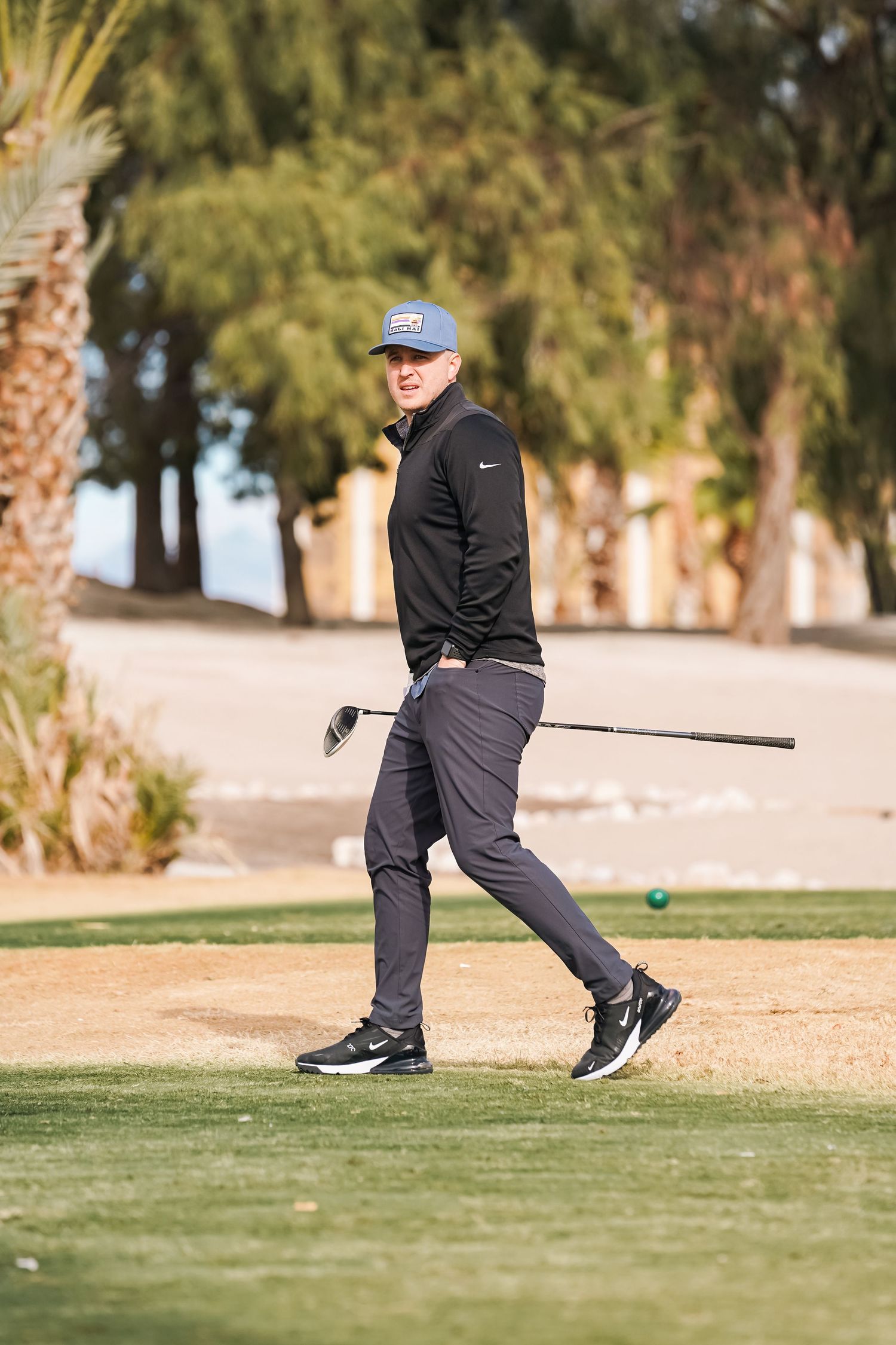 Golfer in dark clothing preparing to hit a shot on the desert golf course.