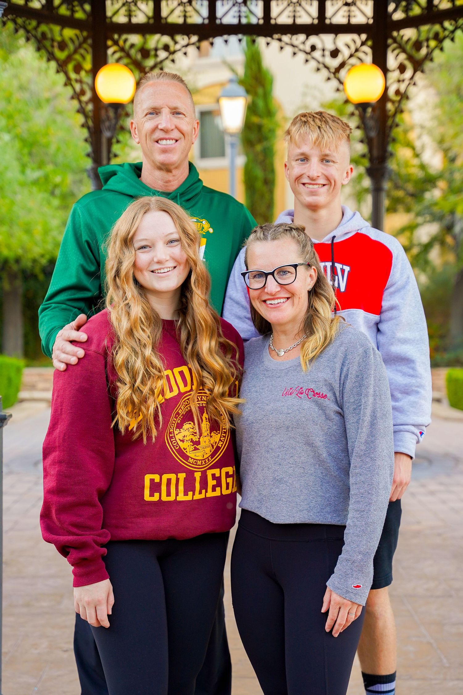 A family group wearing university branded apparel poses together under a decorative gazebo.