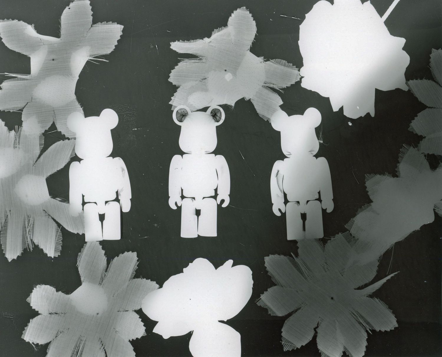 White toy figures arranged with floral silhouettes in black and white composition.