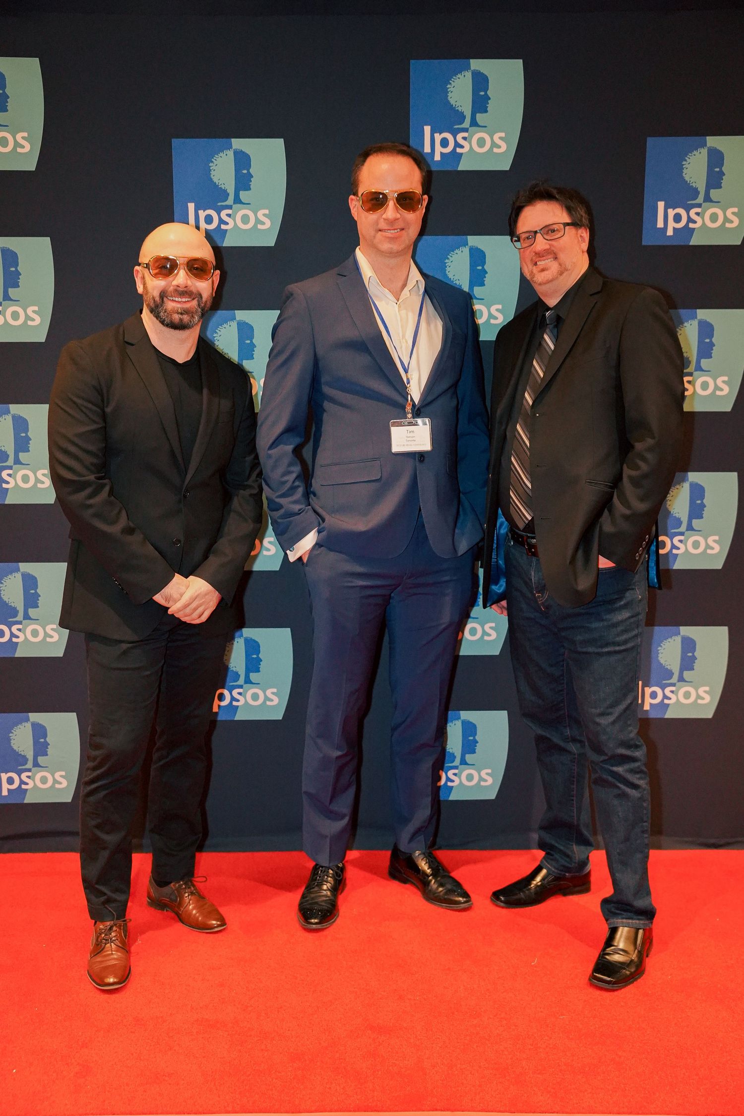 Business professionals standing together on red carpet with Ipsos logos in background.