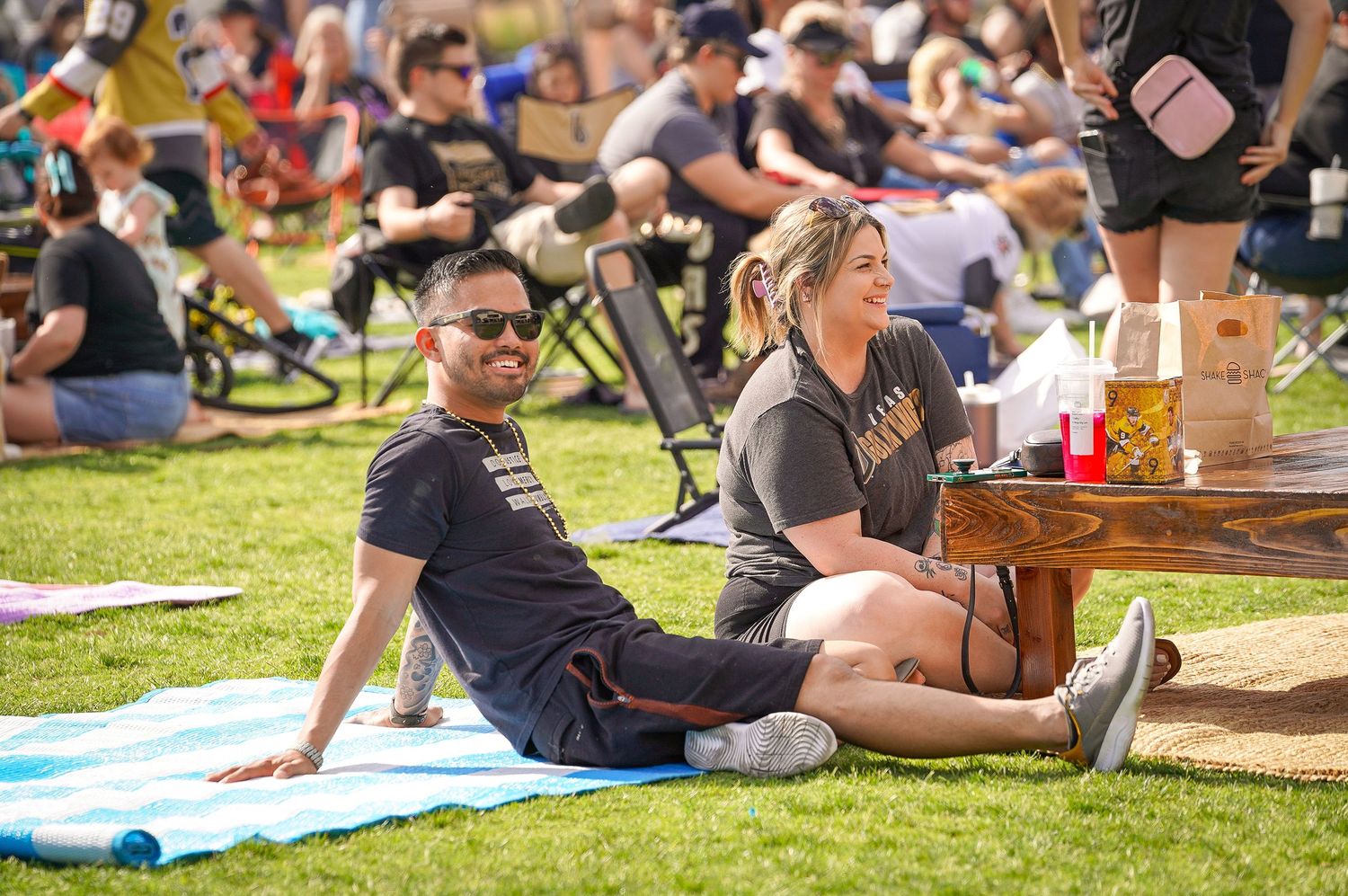 People relaxing on blankets at outdoor festival during sunny day.