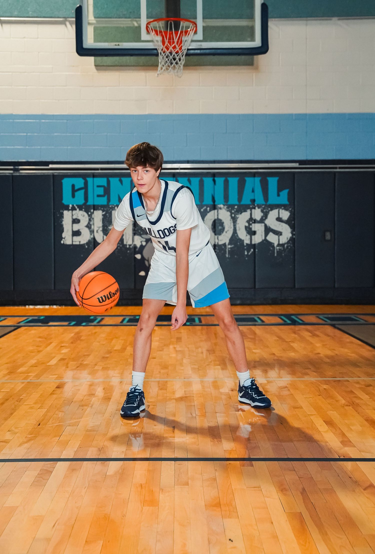 Player demonstrates low defensive stance on basketball court in Bulldogs uniform.