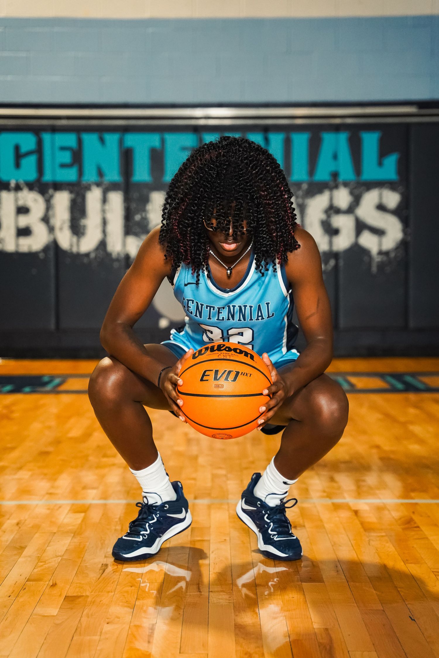 Low angle shot of basketball player in uniform holding ball on gymnasium floor.