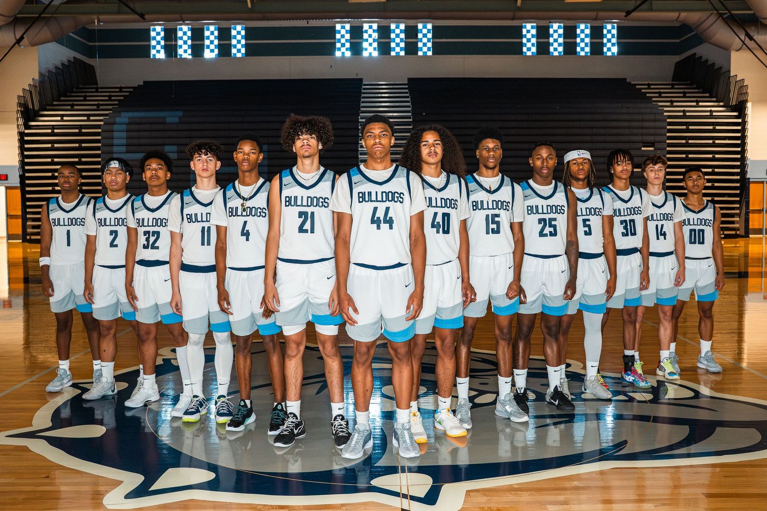 Panoramic basketball team photo showing players lined up in white uniforms on court.