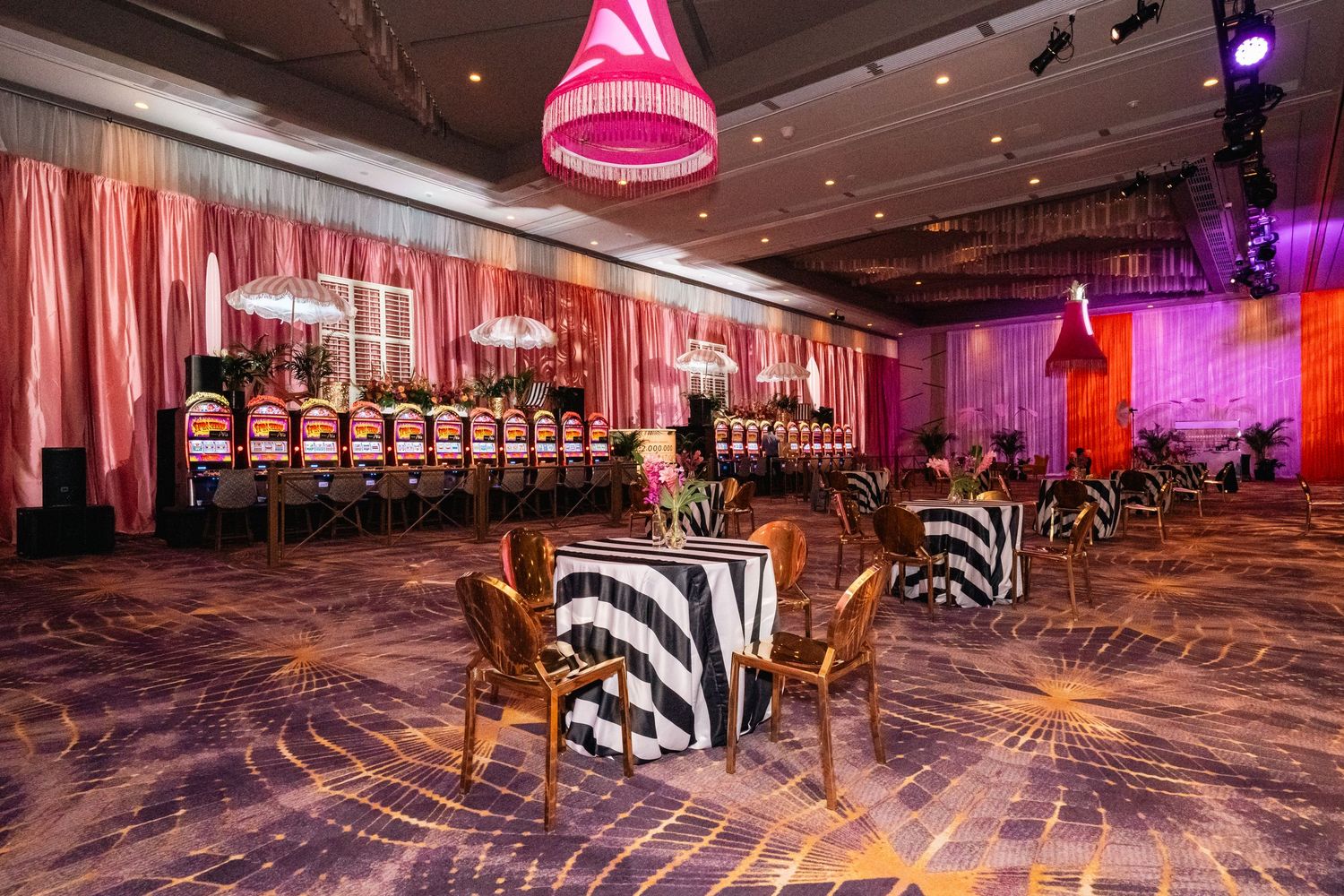 Luxurious casino lounge area with zebra-print chairs and pink drapery under mood lighting.