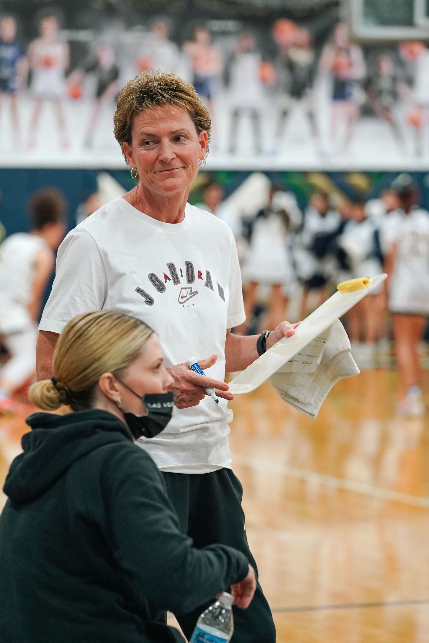 Coaches review notes during basketball game on sideline.