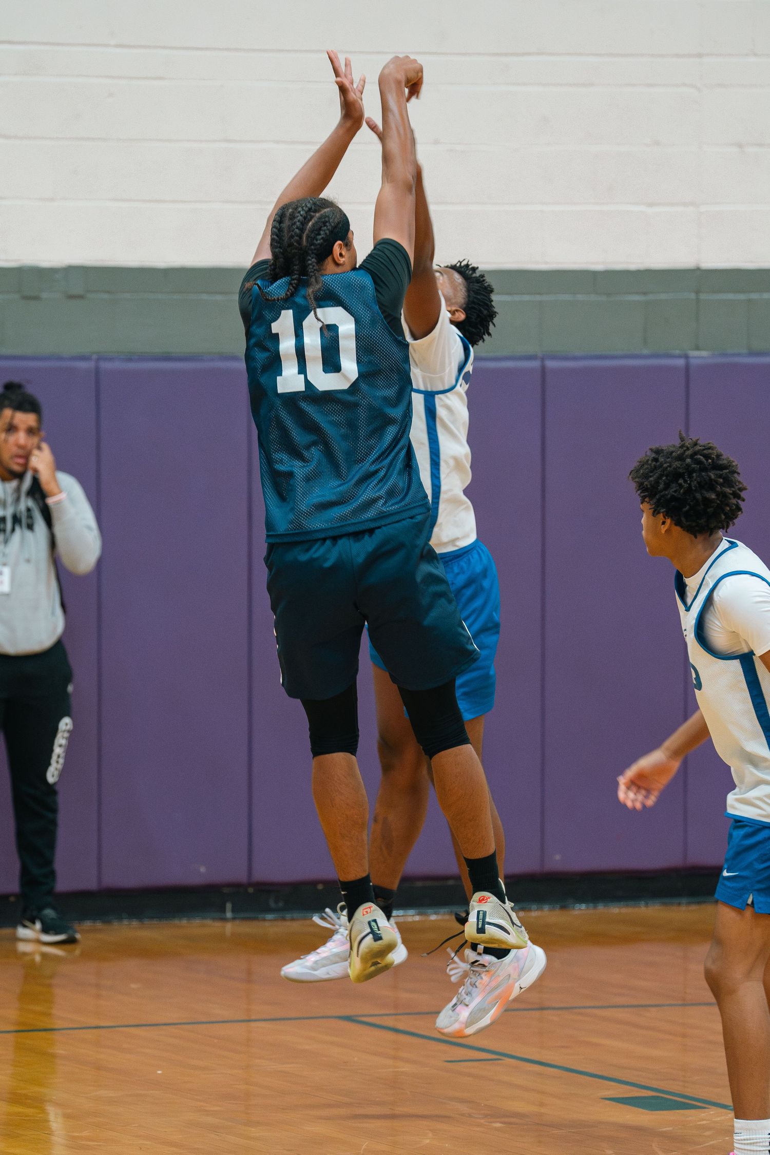 Two basketball players jump high to compete for the ball during an intense game.