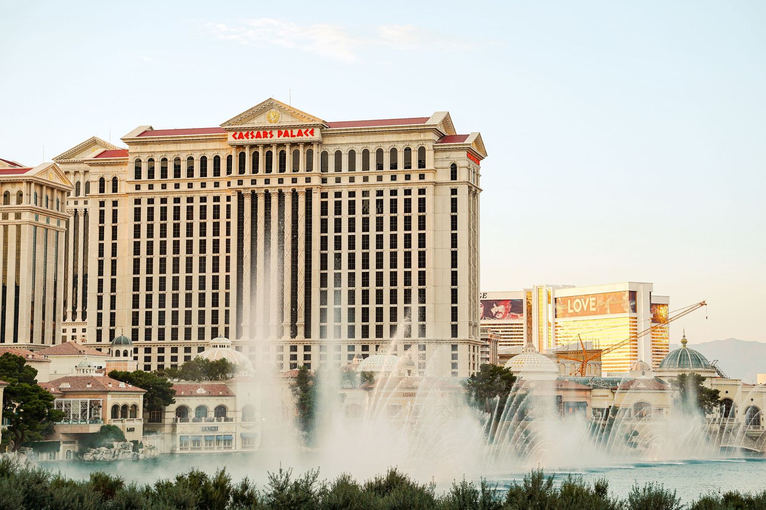 Caesars Palace hotel and casino with dramatic fountain display at dusk in Las Vegas.