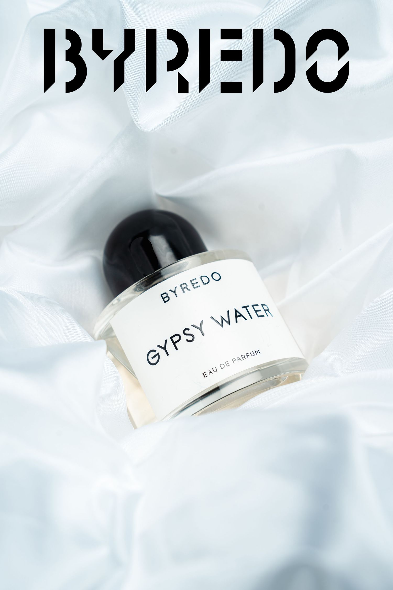 Byredo luxury perfume bottles arranged on white soft fabric background.