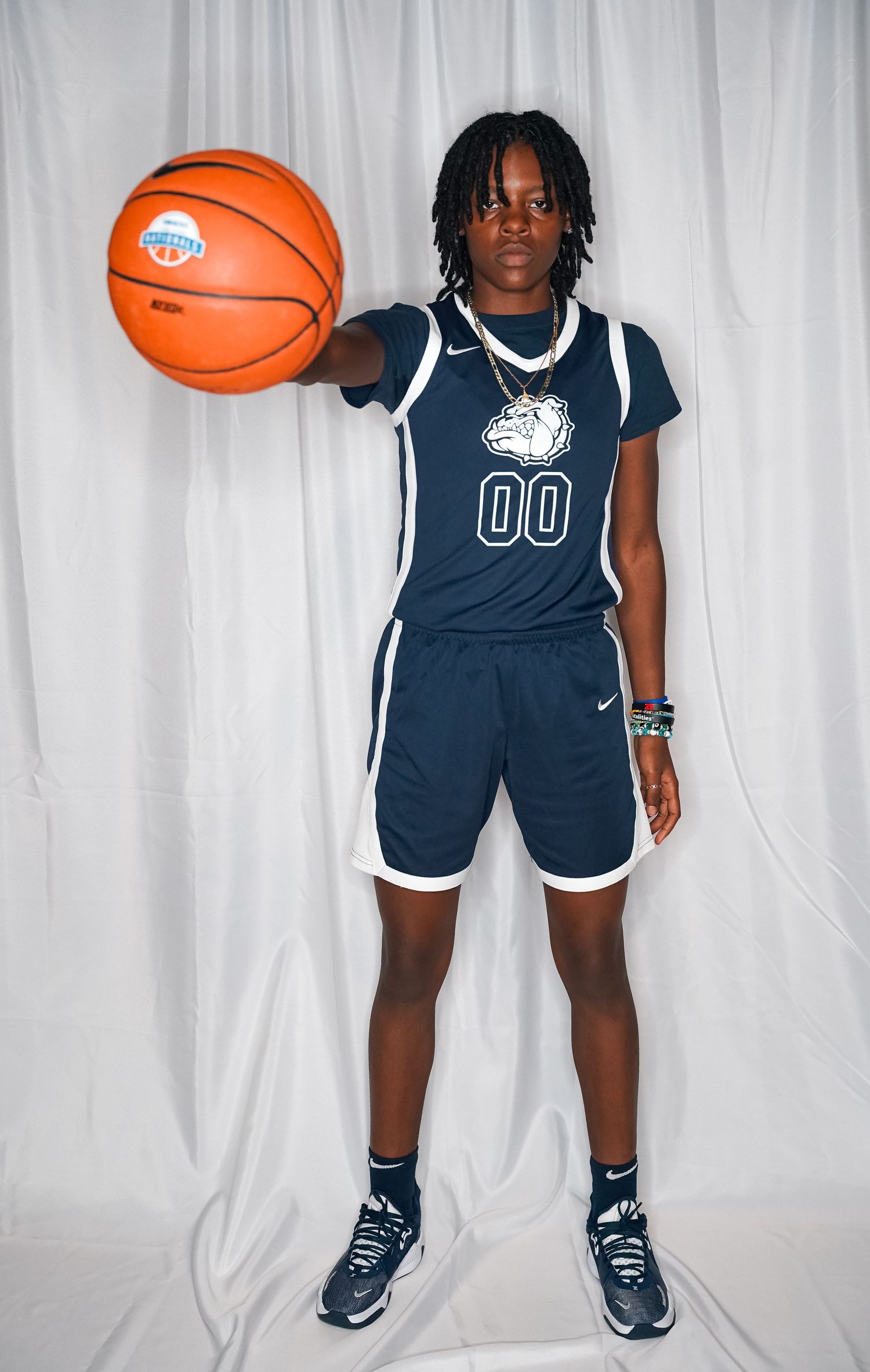 Basketball player in navy jersey number 00 holds ball during team photo session.