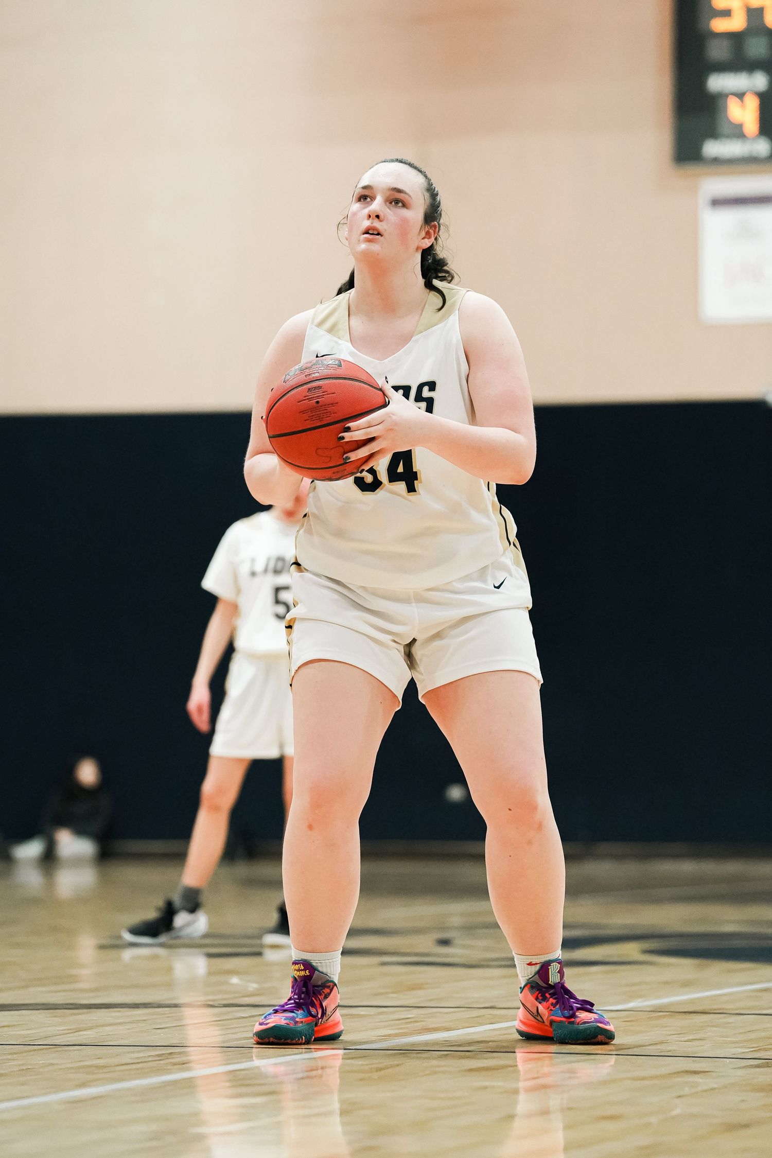 Basketball player prepares to shoot while positioned in triple threat stance on court.