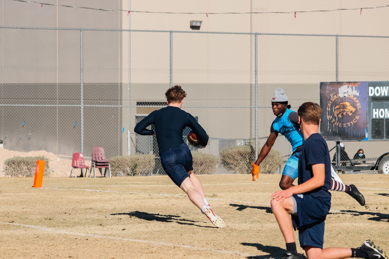 Athletes run across a grass field during a competitive flag football match.
