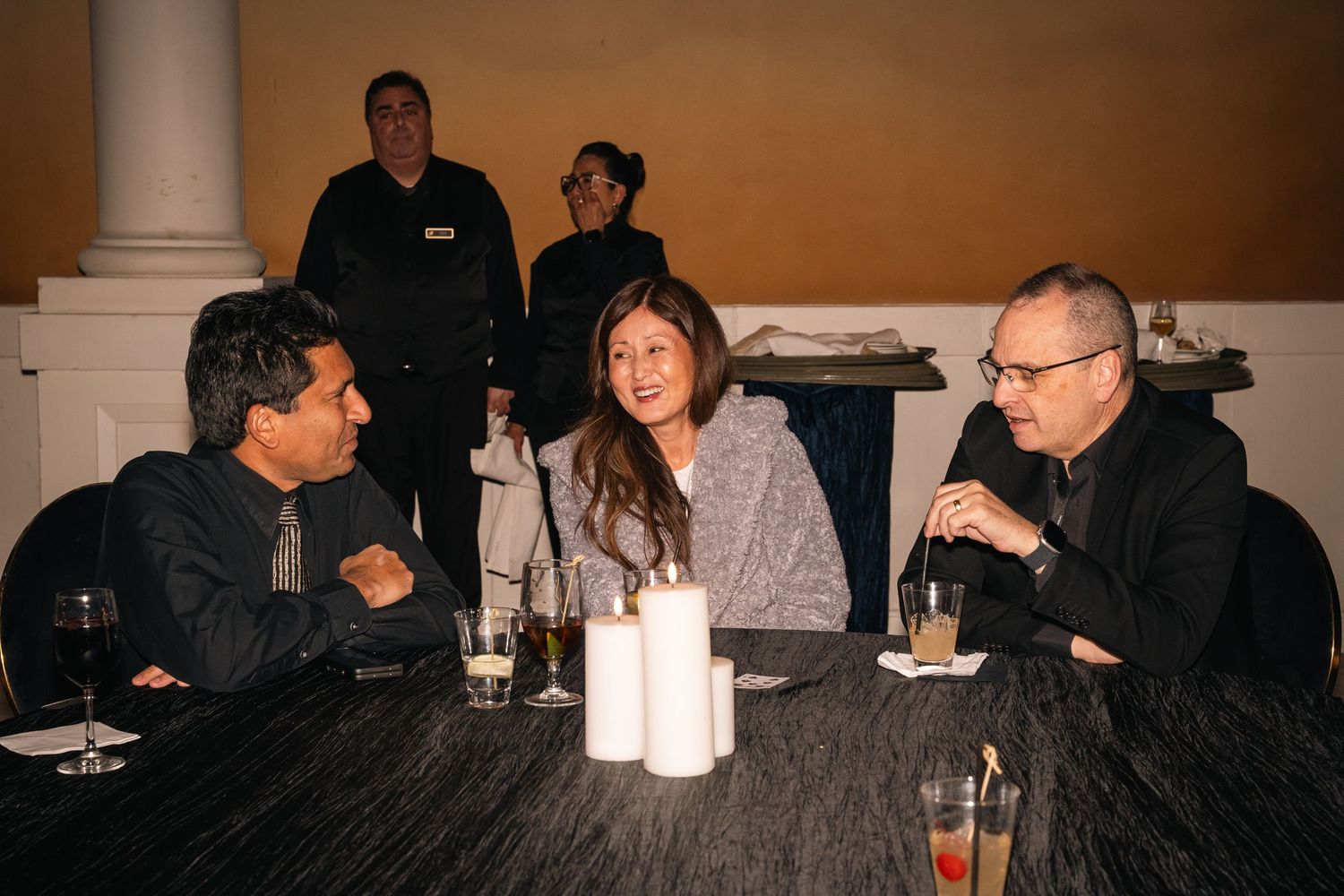 Small group having conversation at round table during evening social event.
