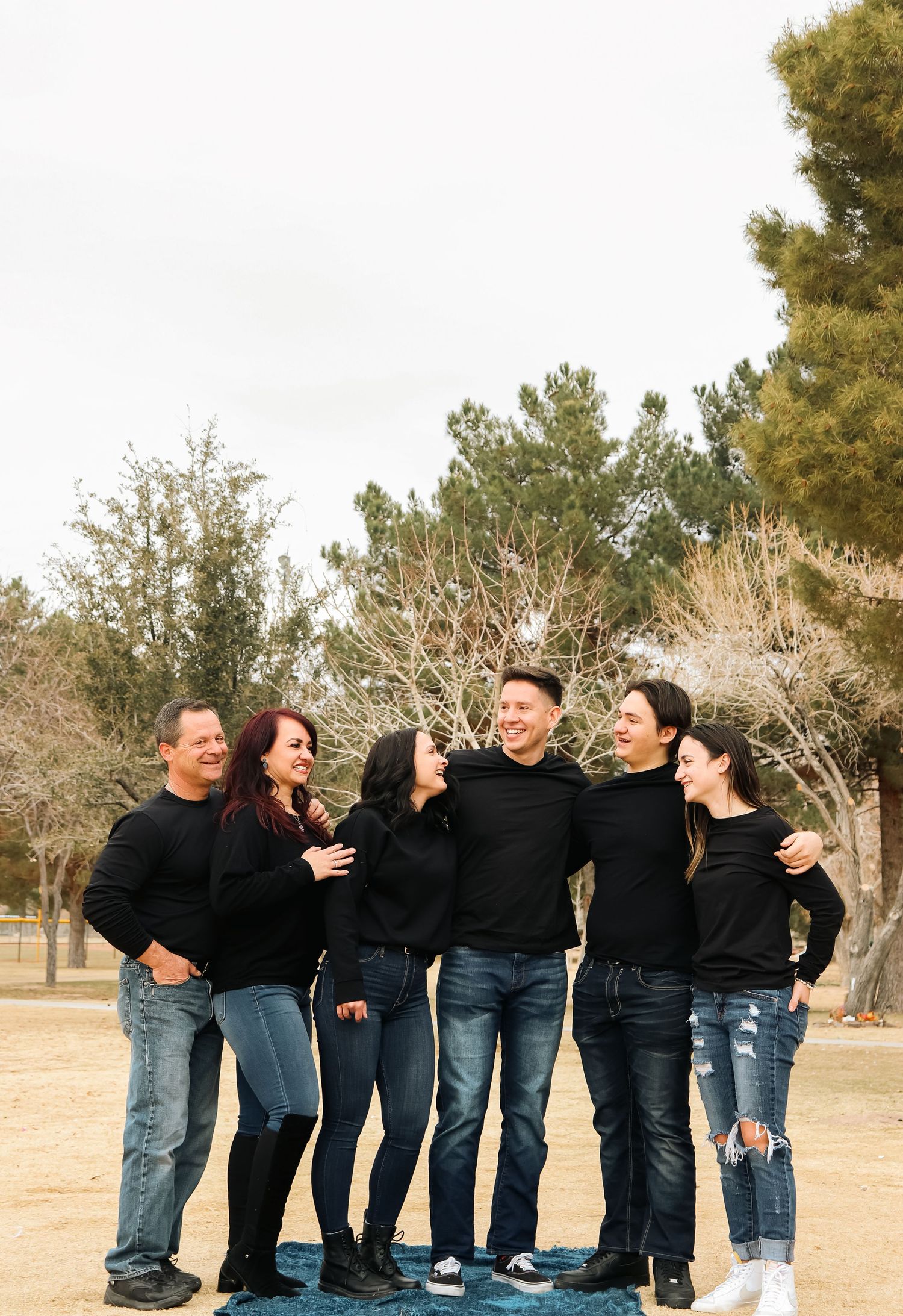 Group of five people wearing black tops and jeans standing together outdoors.