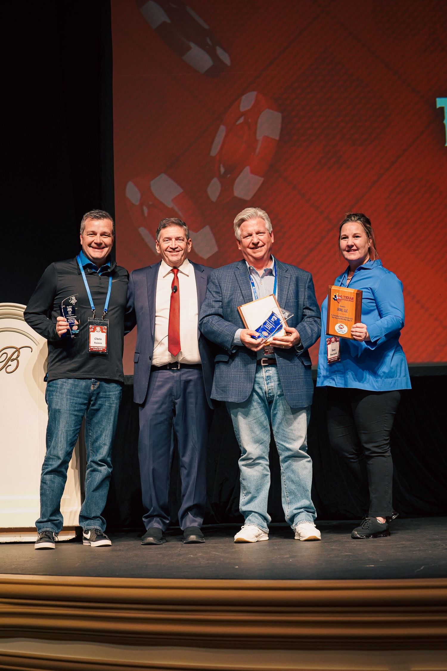 Group of people in casual and formal wear lined up on stage during an event.